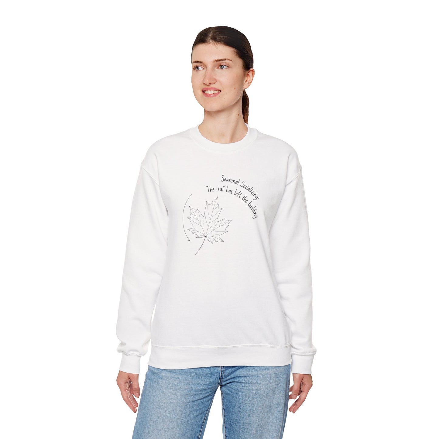 Woman wearing a white sweatshirt with a design and text 'Seasonal Socializing, The leaf has left the building' on a white background