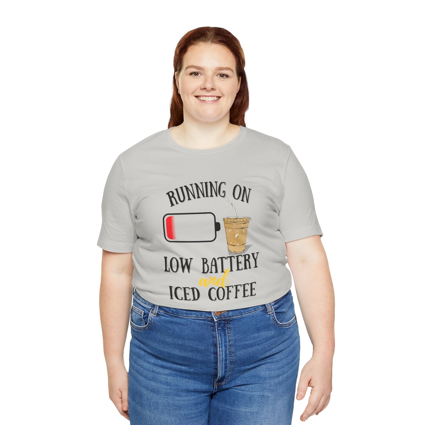 Person wearing a gray t-shirt with a humorous design and text 'Running on low battery and iced coffee' on a white background