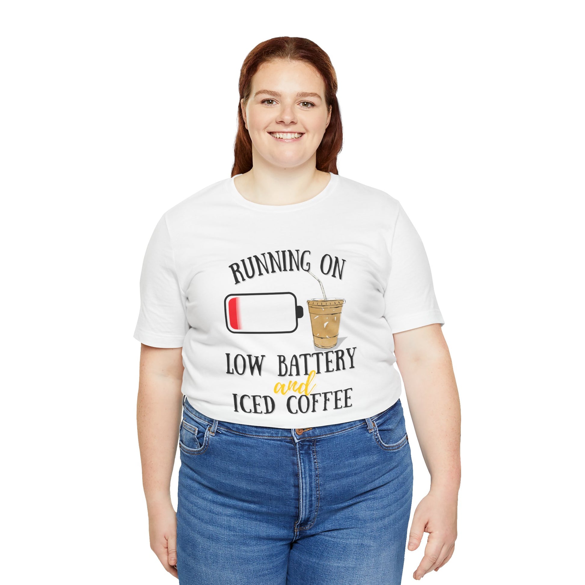 Person wearing a white t-shirt with a humorous graphic and text 'Running on low battery and iced coffee' on a white background