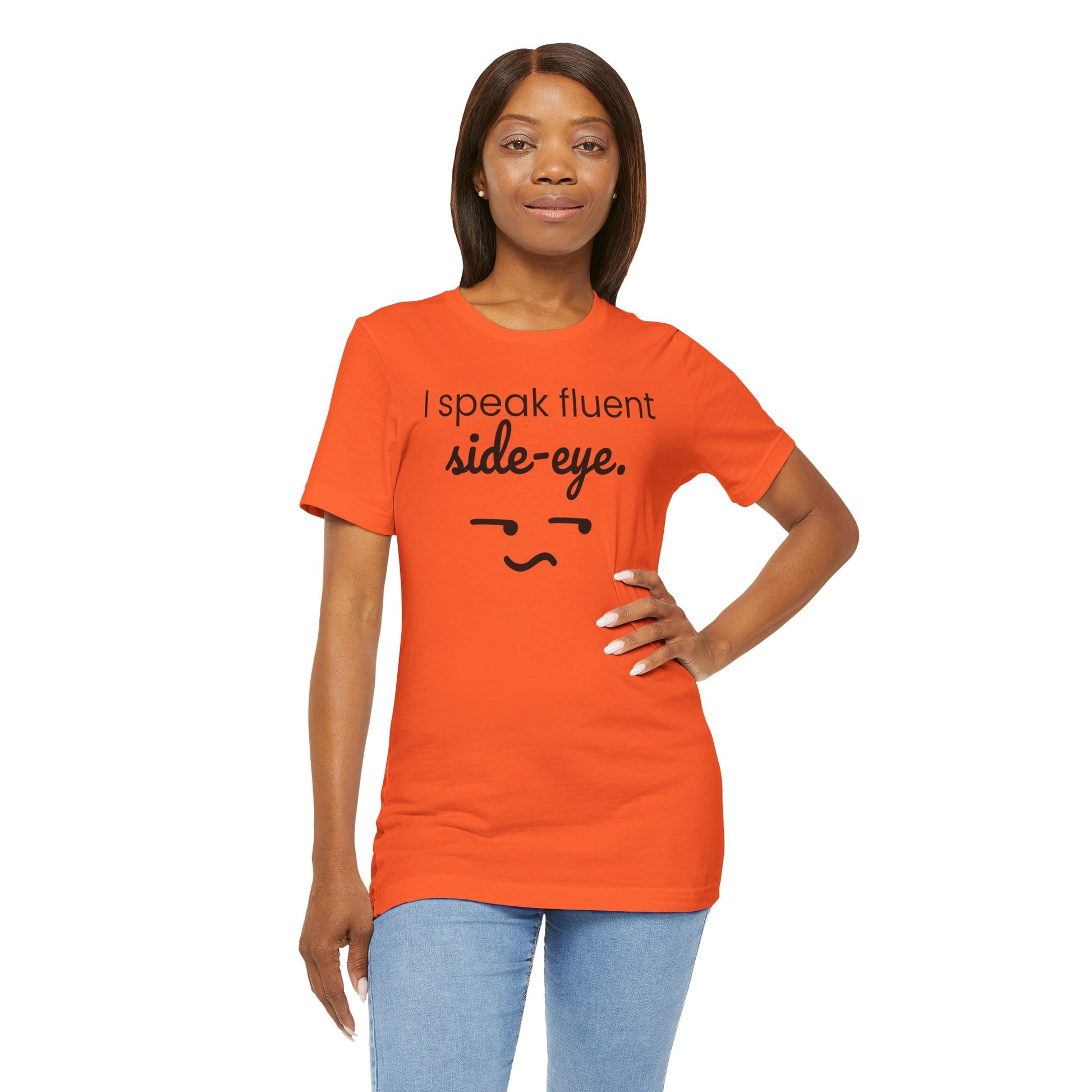 Woman wearing an orange t-shirt with text 'I speak fluent side eye' and a smiley face on a white background