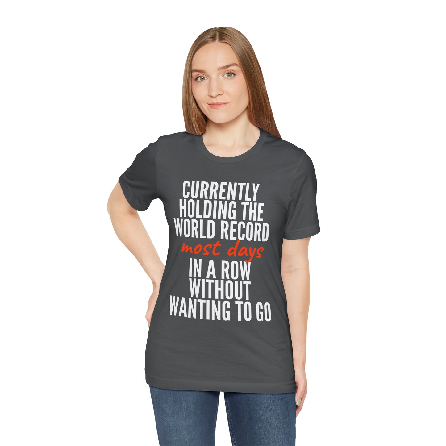 Woman wearing a gray t-shirt with humorous text 'Currently holding the world record most days in a row without wanting to go' design on a white background