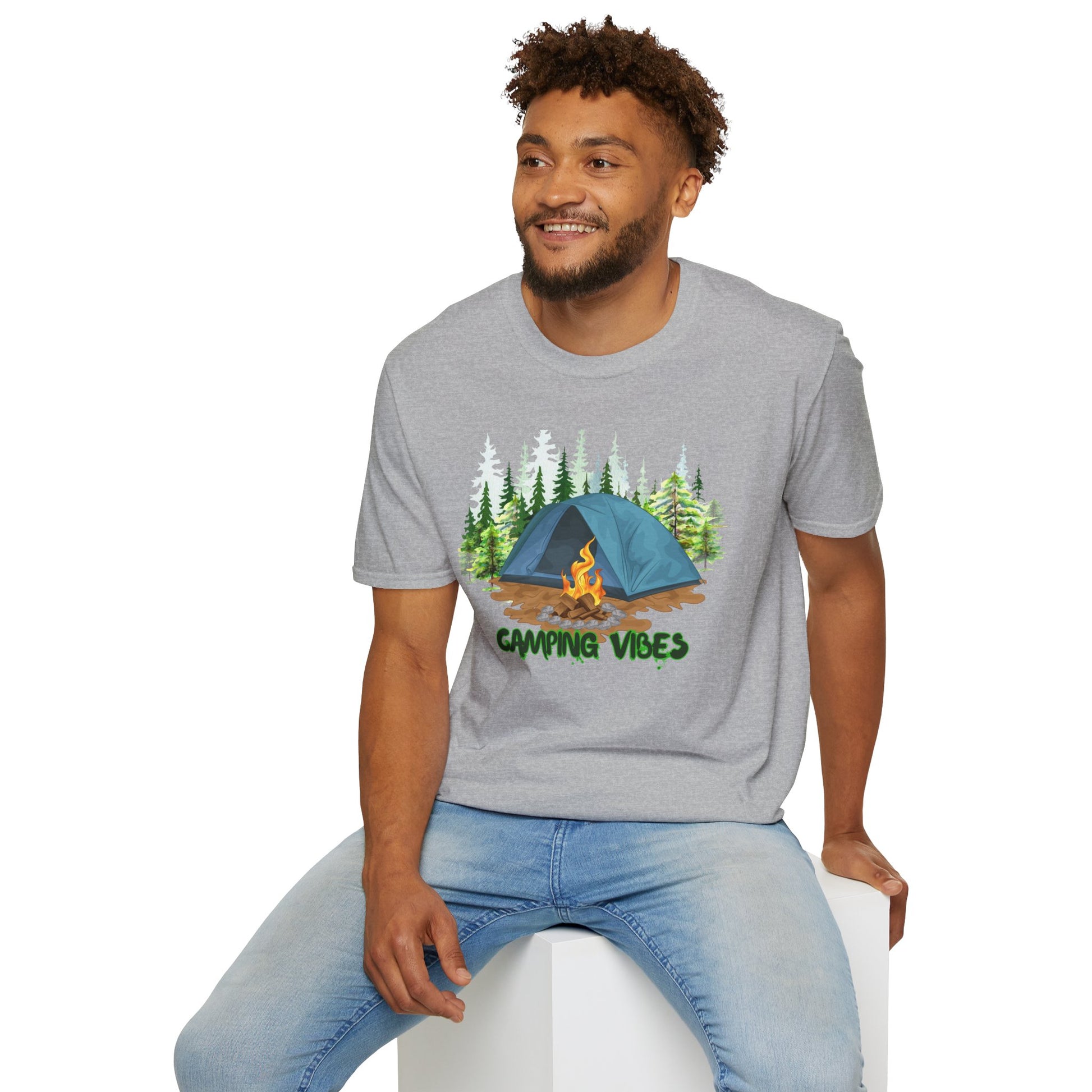 Man wearing a gray t-shirt with a camping design and text, sitting on a white stool.