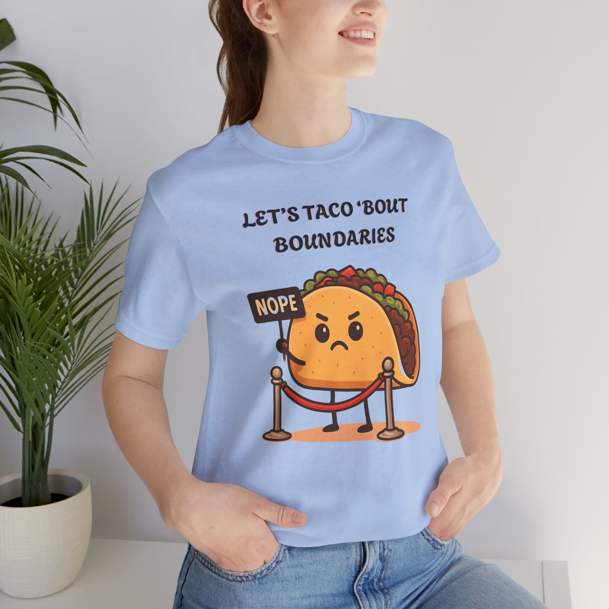 Person wearing a light blue t-shirt with a cartoon taco graphic and text 'Let's taco 'bout boundaries'.
