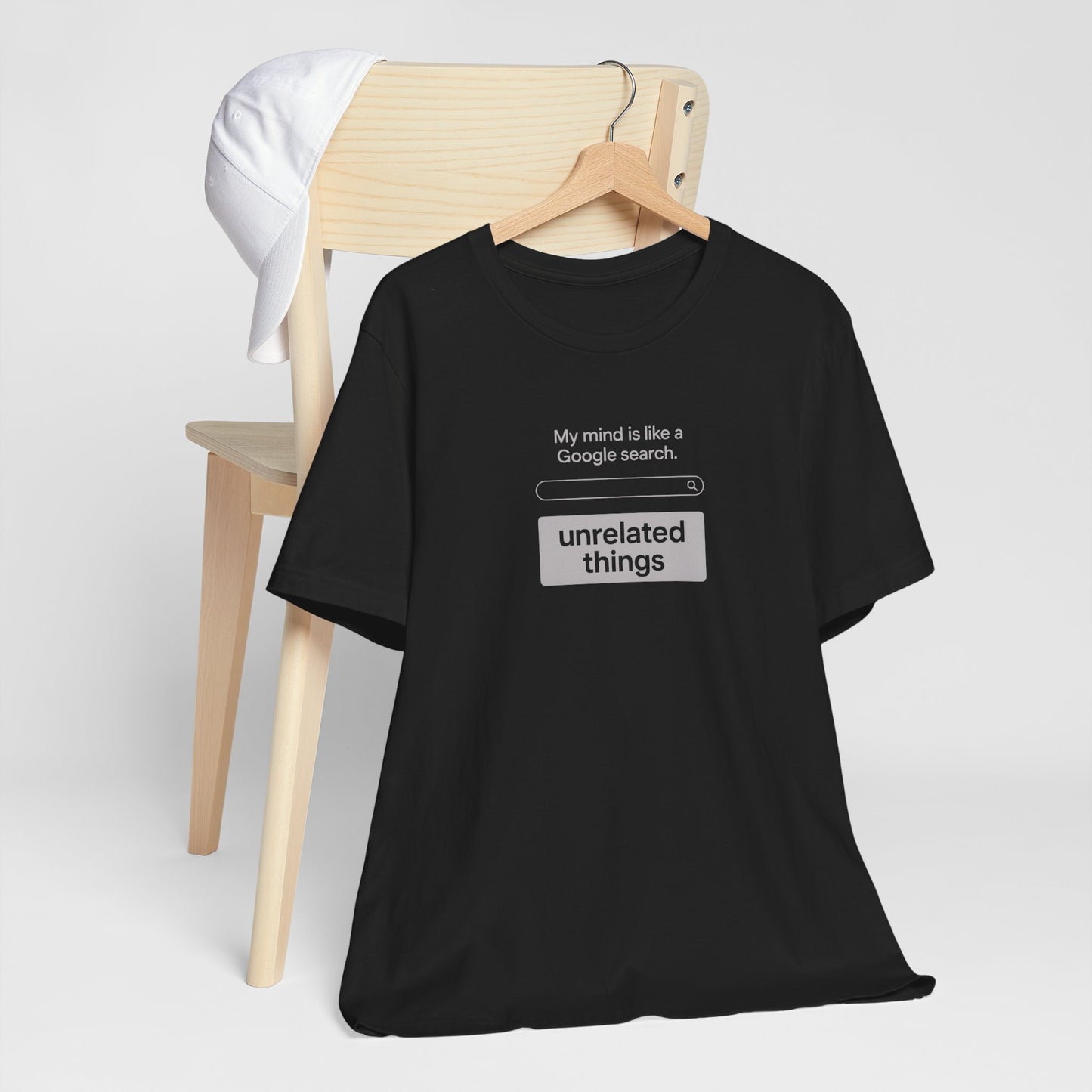 Black t-shirt with humorous text design on a white background. T-shirt has search bar graphic with text above that says, 'My mind is like a Google search' and text below that says, 'unrelated things.'