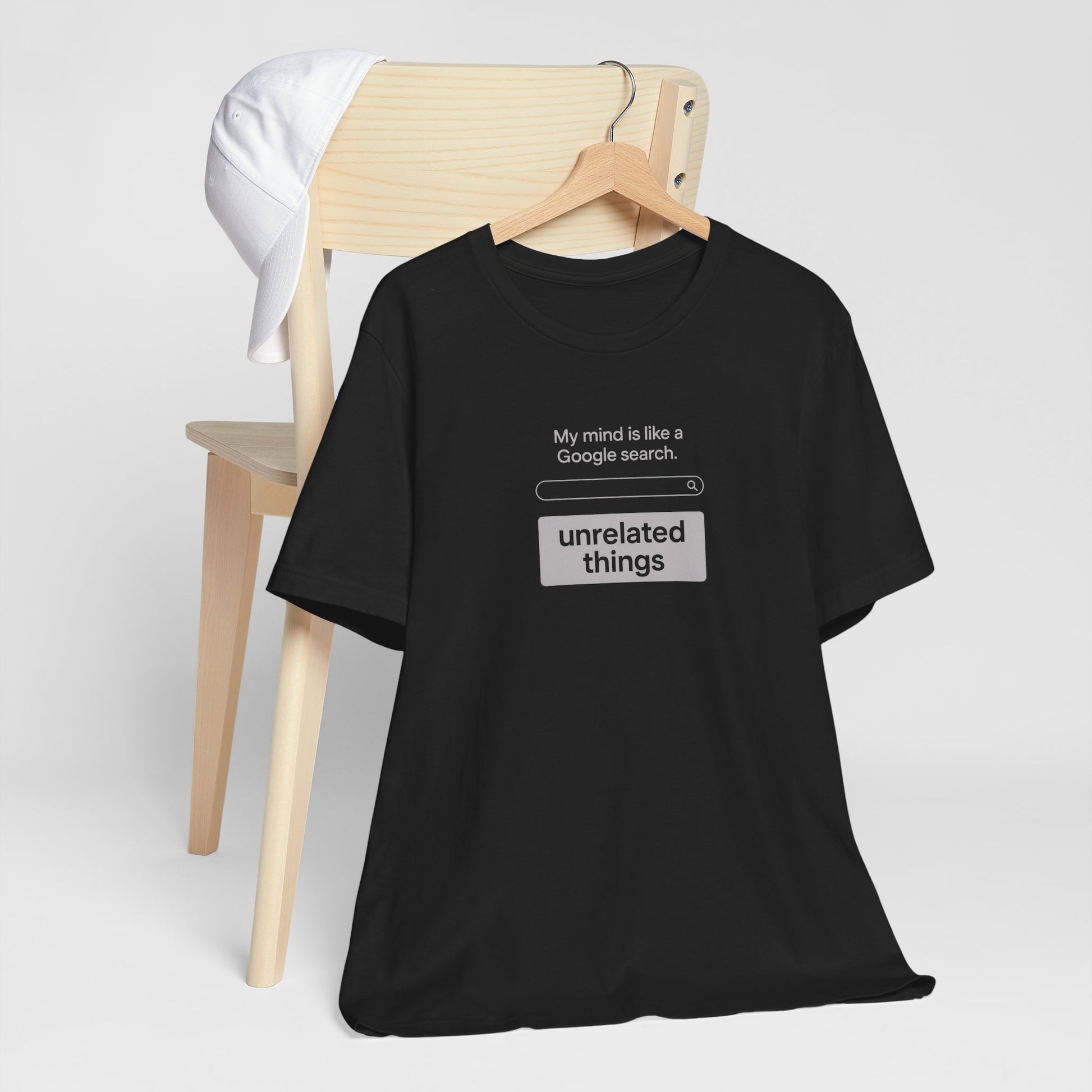 Black t-shirt with humorous text design on a white background. T-shirt has search bar graphic with text above that says, 'My mind is like a Google search' and text below that says, 'unrelated things.'