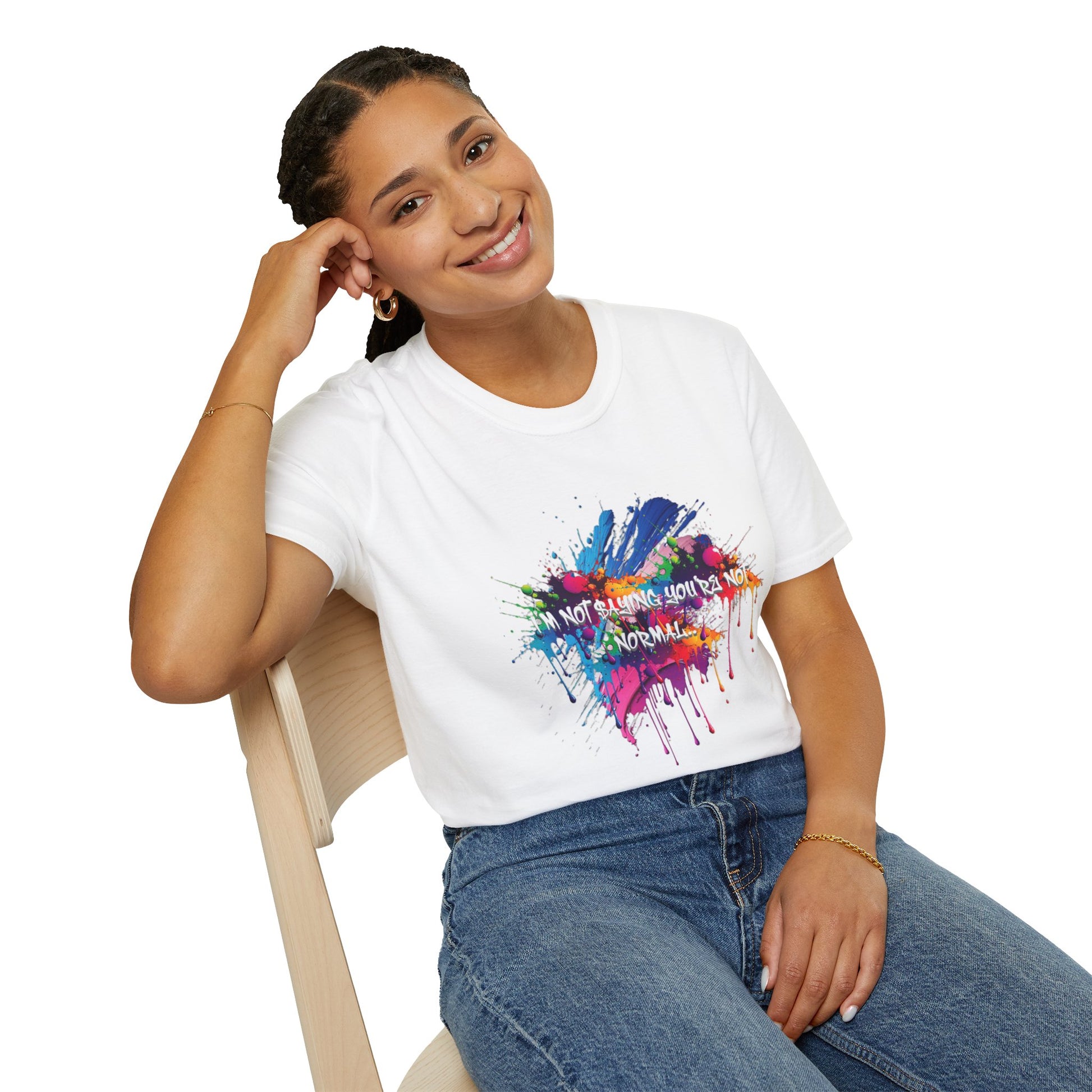 Person wearing a white t-shirt with colorful graphic design and text 'I'm not saying you're not normal' sitting on a chair.