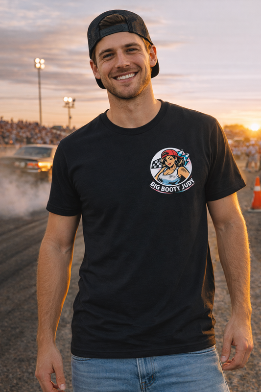 Man wearing a black t-shirt with a 'Big Booty Judy' logo graphic design on a race track at sunset