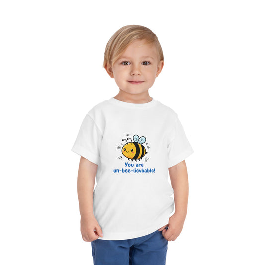 Child wearing a white 'You Are Un-Bee-Lievable' toddler t-shirt with cute bee graphic – Bella+Canvas 3001T on a white background