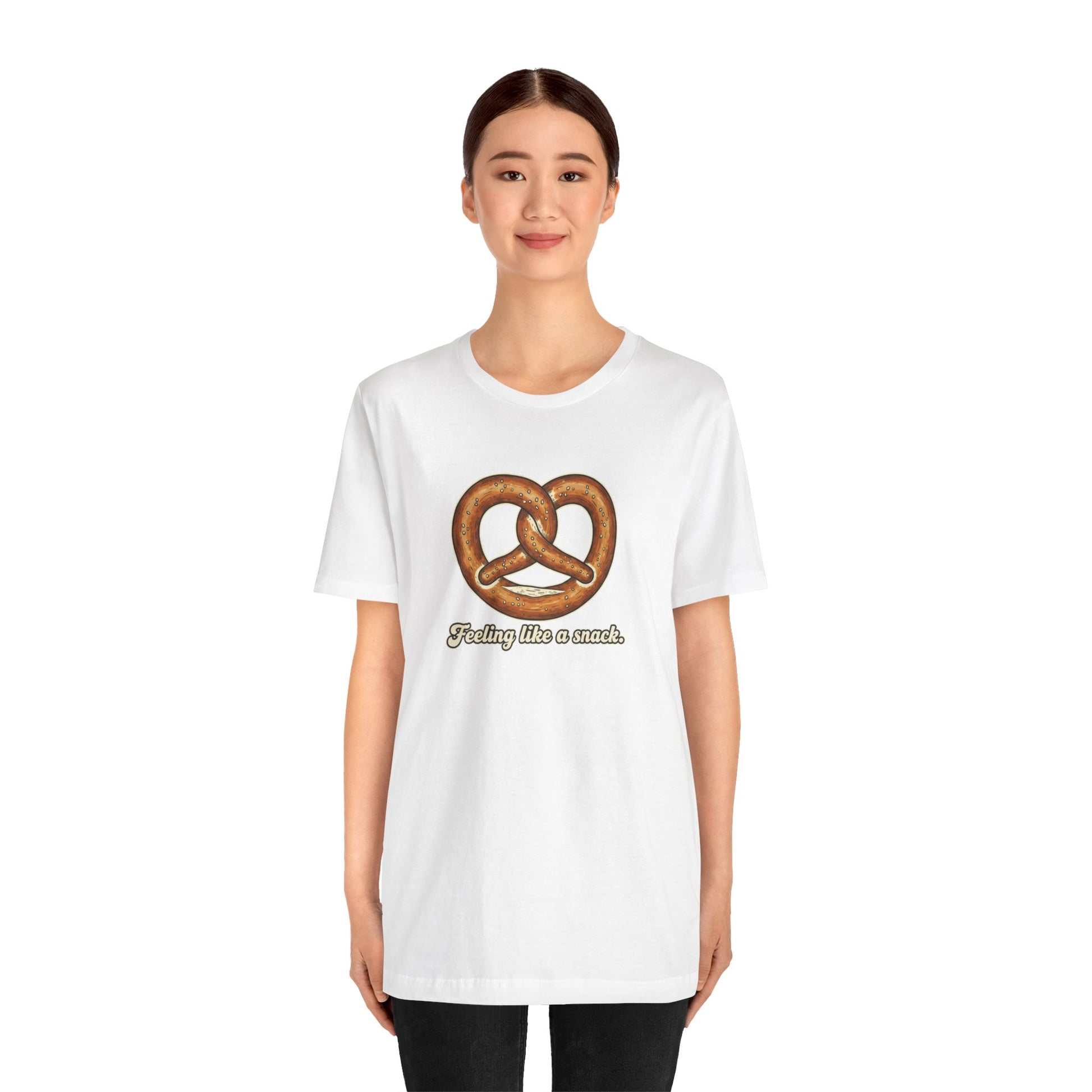 Person wearing a white t-shirt with a pretzel graphic and text 'Feeling like a snack' on a white background
