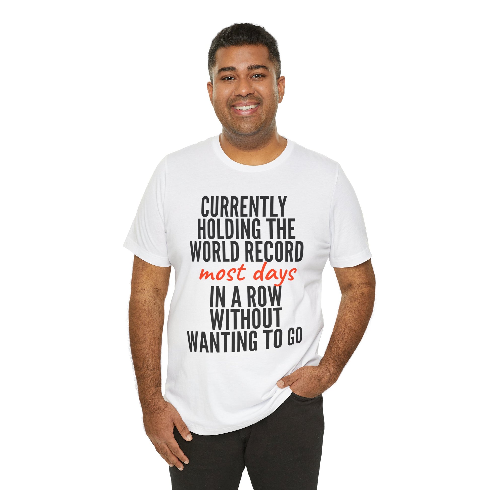 Man wearing a white t-shirt with humorous text 'Currently holding the world record most days in a row without wanting to go' design on a white background