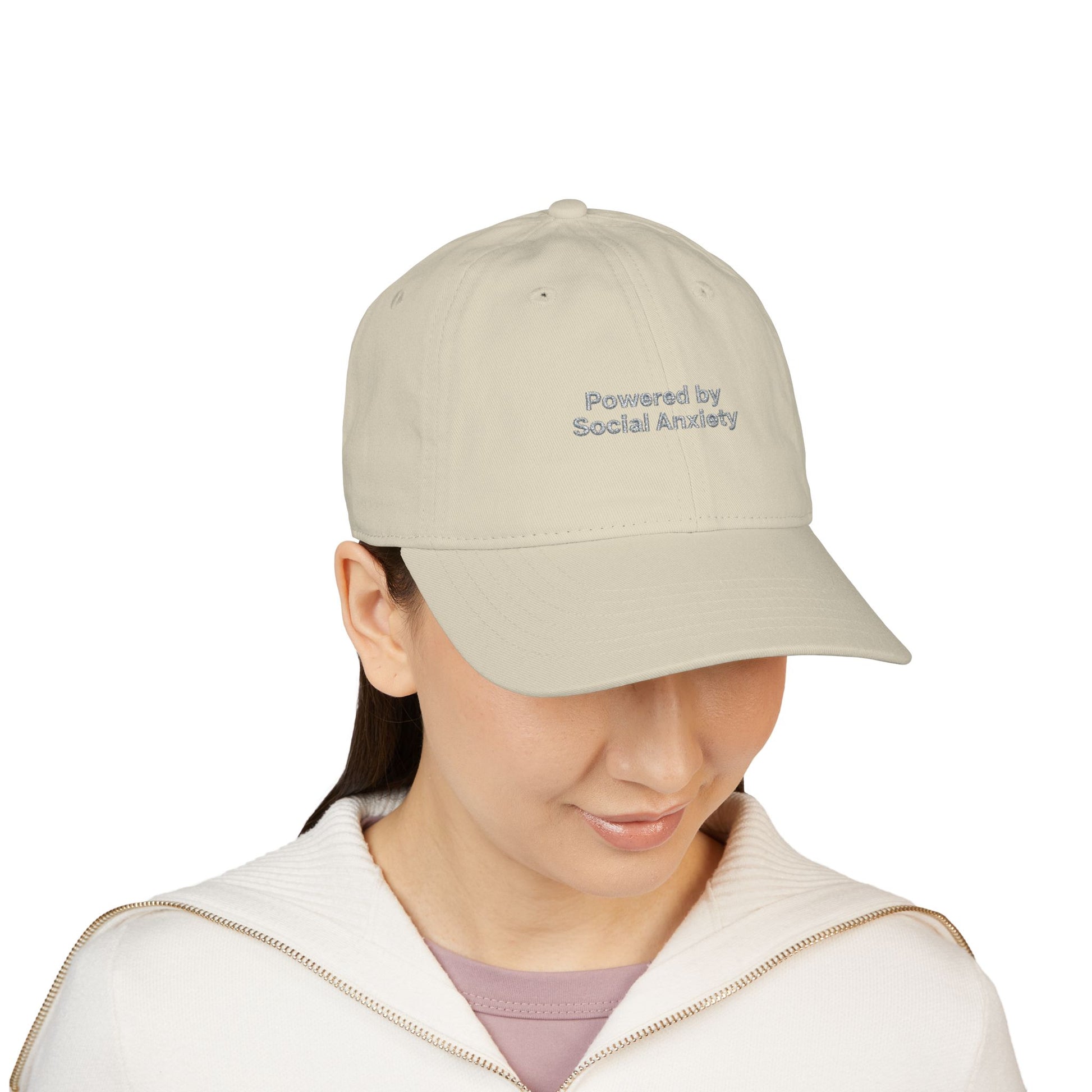 Person wearing a beige cap with 'Powered by Social Anxiety' text on a white background