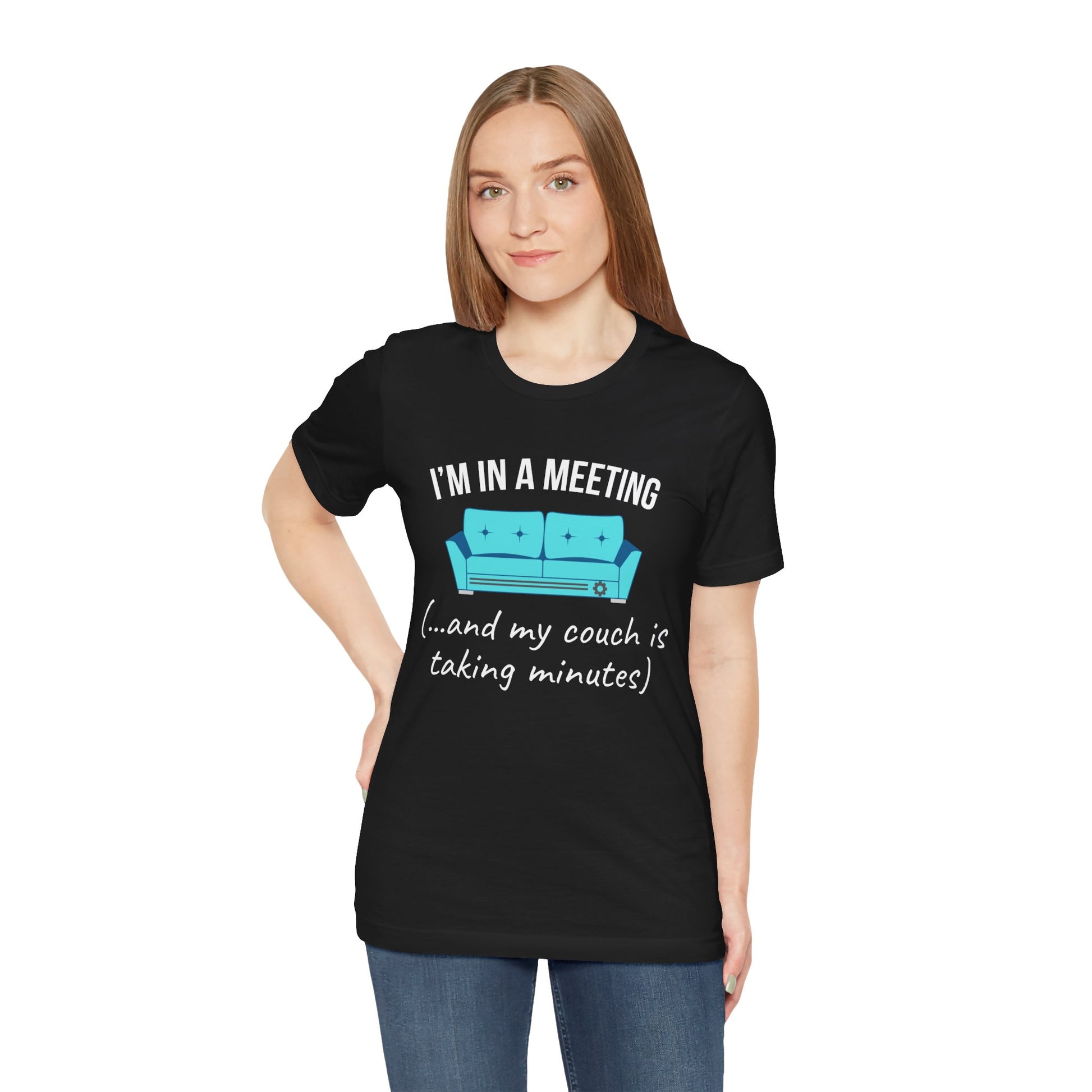 Person wearing a black t-shirt with humorous text 'I'm in a meeting (...and my couch is taking minutes)'and graphic design on a white background