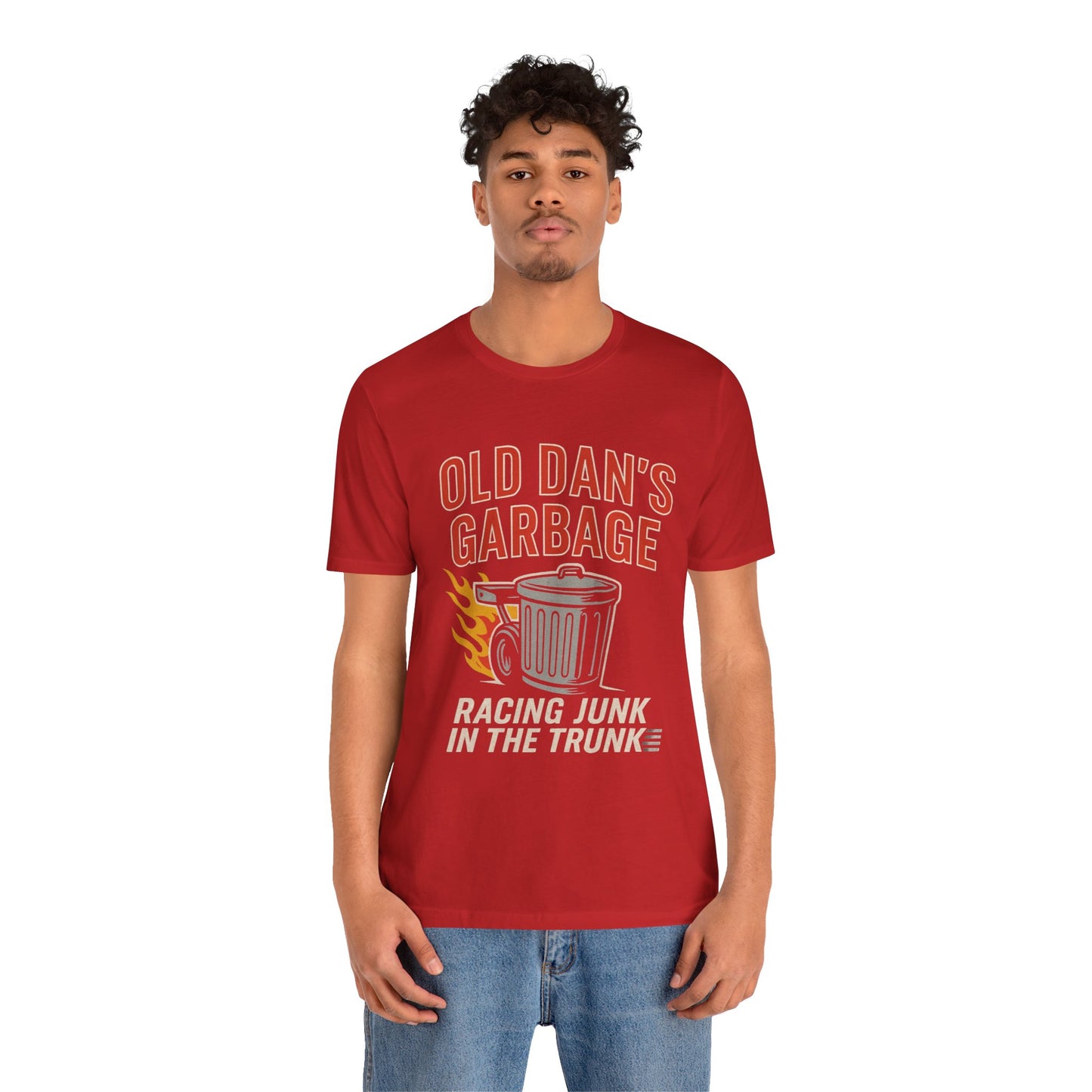 Person wearing a red graphic T‑shirt featuring the bold red and white text “Old Dan’s Garbage” above a flaming garbage can illustration, with the tagline “Racing Junk in the Trunk” below. Funny drag racing parody shirt with retro racing flames, checkered flag background, and humor‑driven hot rod style, perfect for car enthusiasts and gearhead apparel fans.
