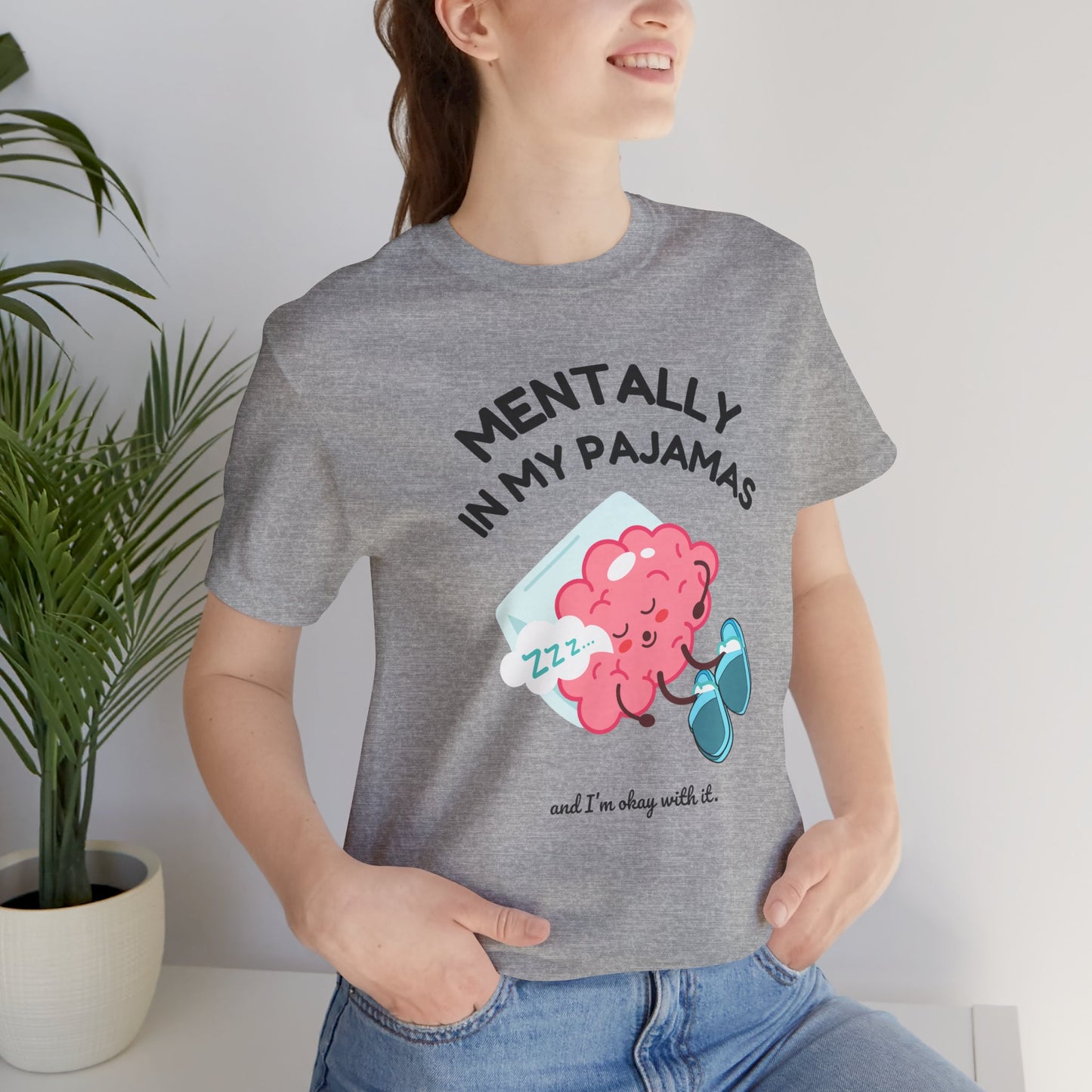 Person wearing a gray t-shirt with a brain graphic and text 'Mentally in my pajamas and I'm ok with it', standing indoors.