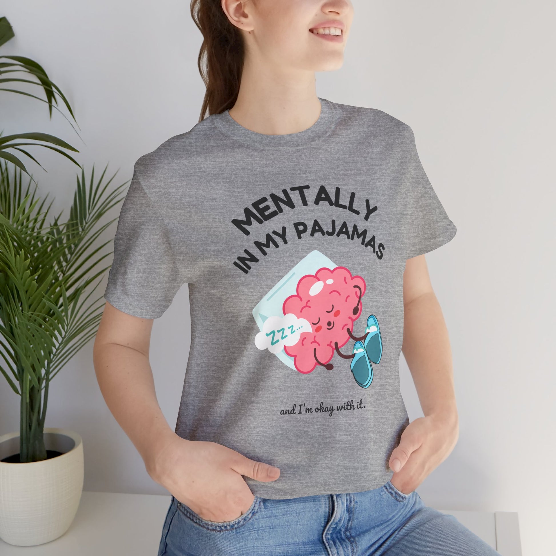 Person wearing a gray t-shirt with a brain graphic and text 'Mentally in my pajamas and I'm ok with it', standing indoors.