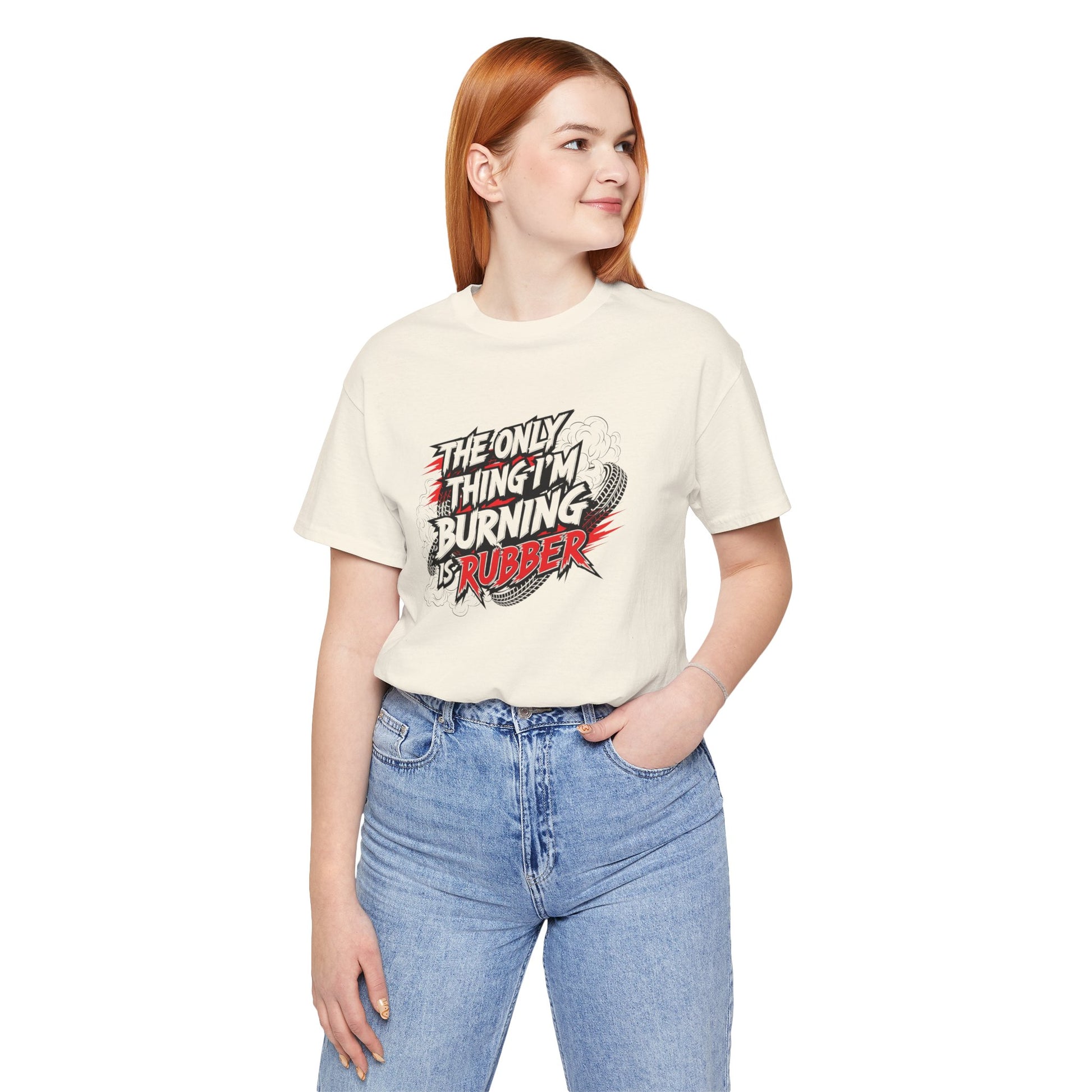 Person wearing a cream t-shirt with a graphic design and text 'The only thing I'm burning is rubber', standing against a white background