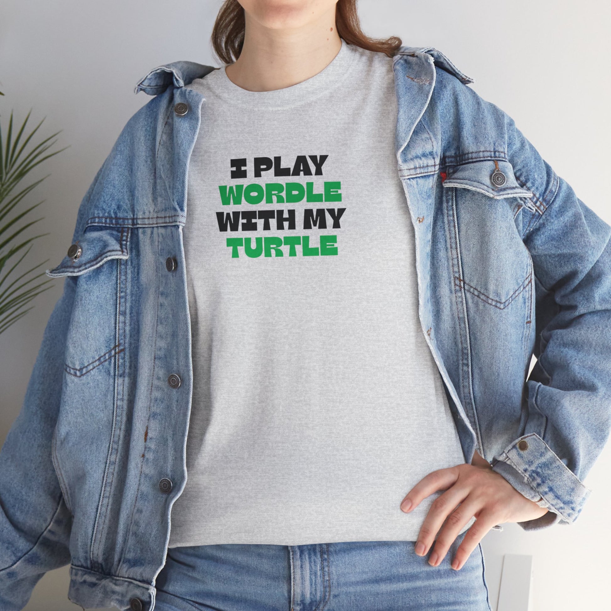 Person wearing a gray t-shirt with 'I Play Wordle With My Turtle' text, paired with a denim jacket.
