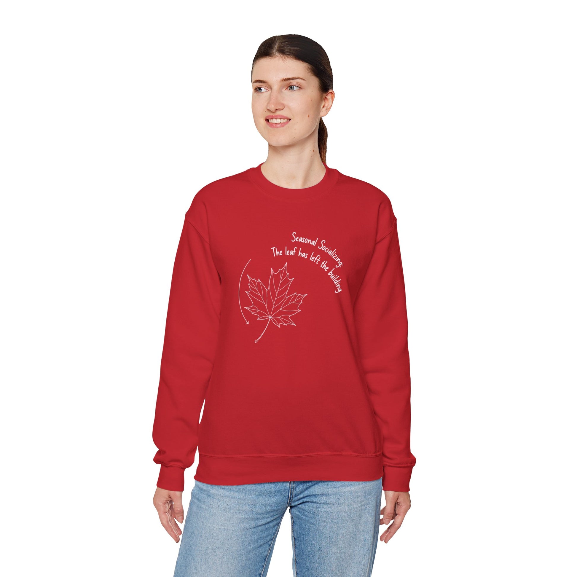 Person wearing a red sweatshirt with a leaf design and text 'Seasonal Socializing, The leaf has left the building' on a white background