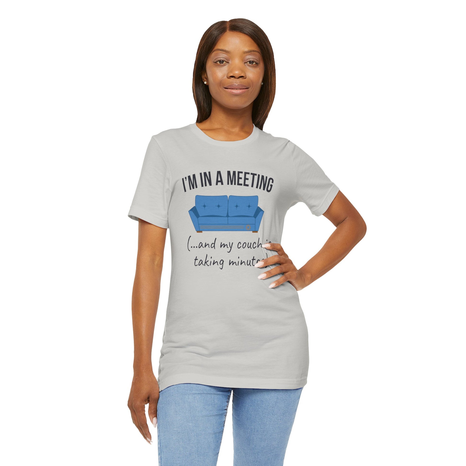Woman wearing a gray t-shirt with a graphic and text 'I'm in a meeting (...and my couch is taking minutes)' on a white background