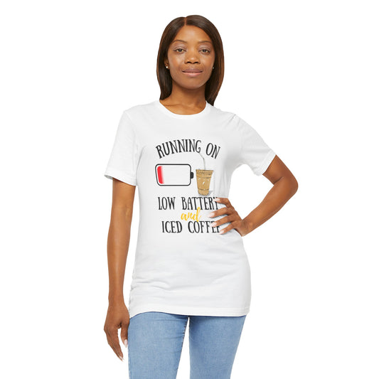 Woman wearing a white t-shirt with a humorous graphic and text 'Running on low battery and iced coffee' on a white background