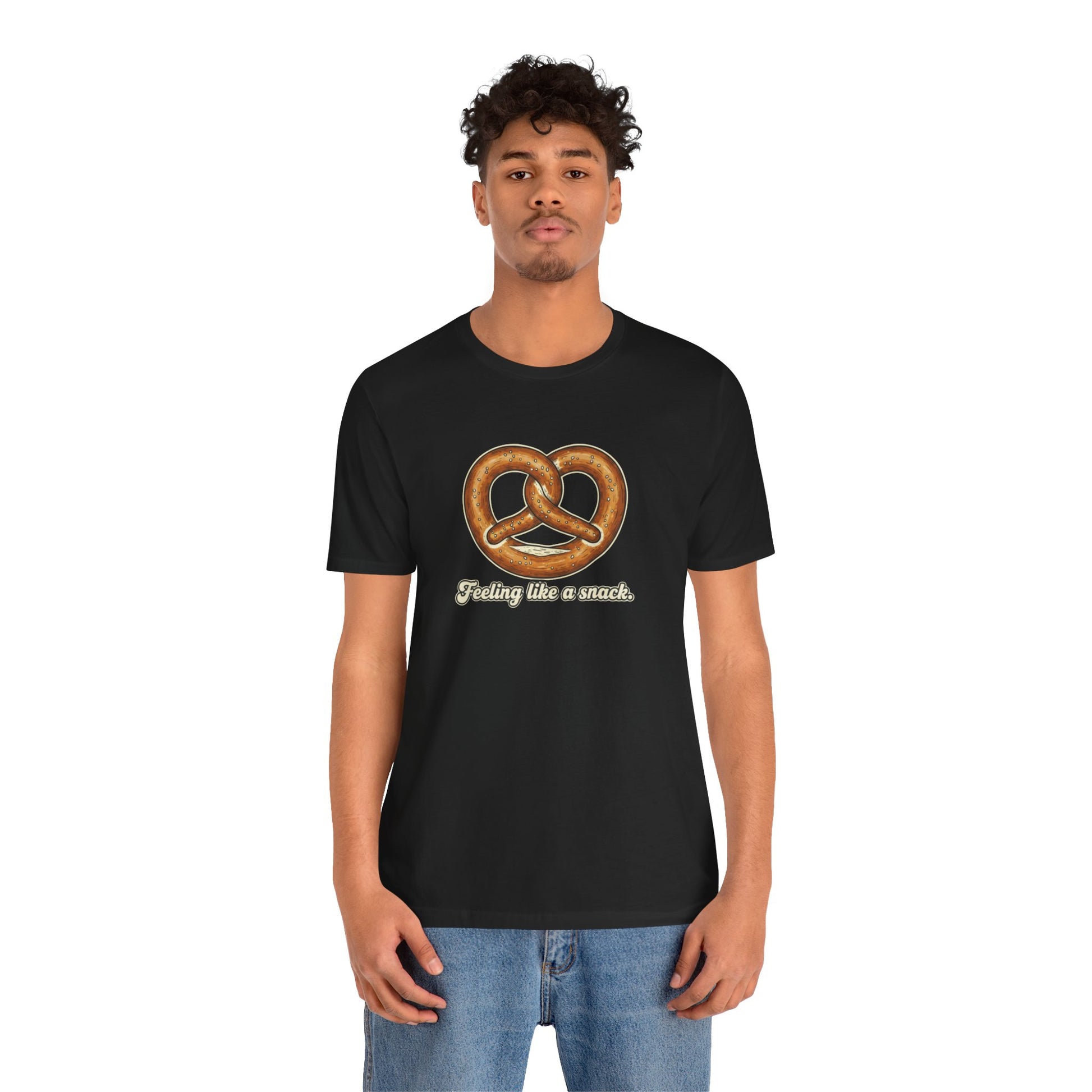 Person wearing a black t-shirt with a pretzel graphic and text that says "Feeling like a snack" on a white background