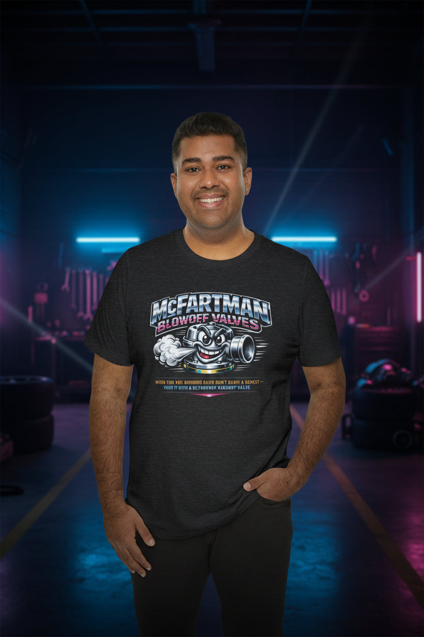Man wearing a black t-shirt with a graphic design and 'McFartman Blowoff Valves When You Are Running Hard Don't Blow A Gasket Vent It With A McFartman Blowout Valve' text in a dark, neon-lit indoor setting