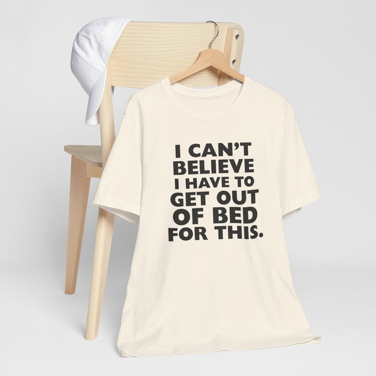 Natural t-shirt with black text 'I can't believe I have to get out of bed for this' on a white background