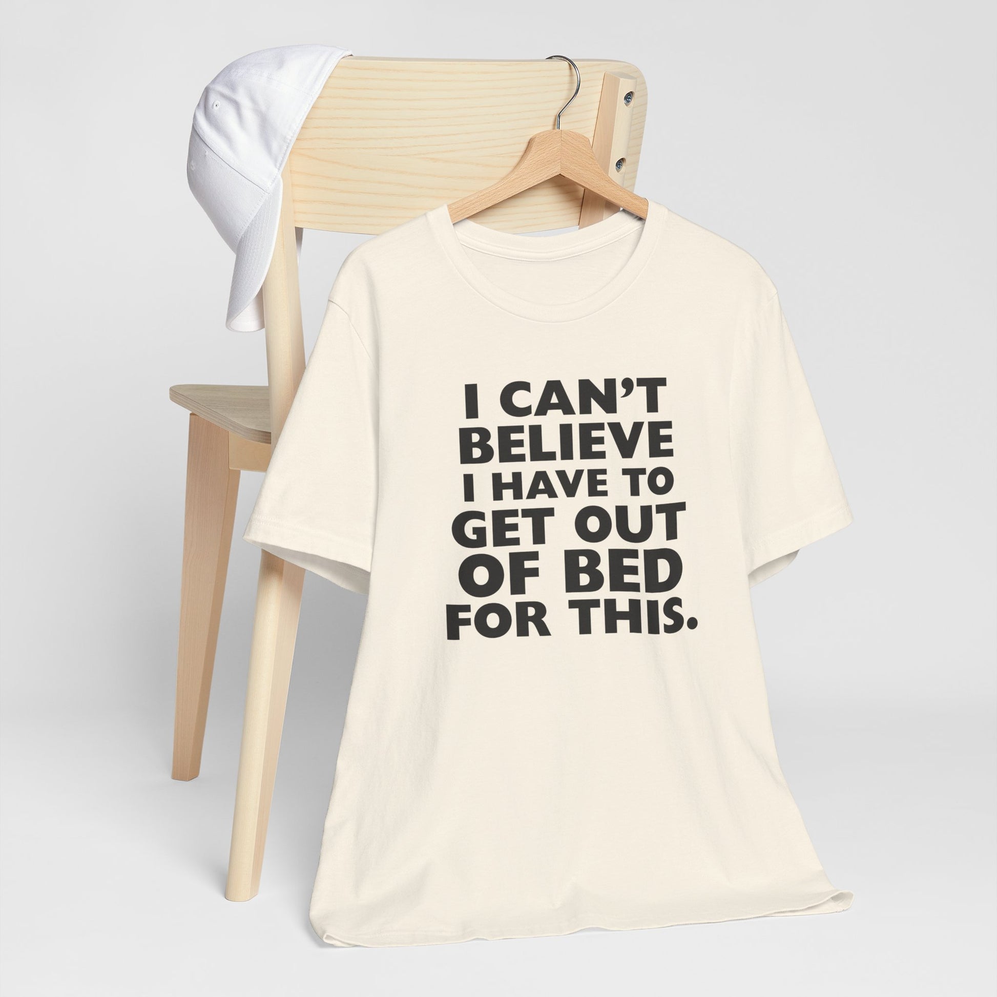 Natural t-shirt with black text 'I can't believe I have to get out of bed for this' on a white background