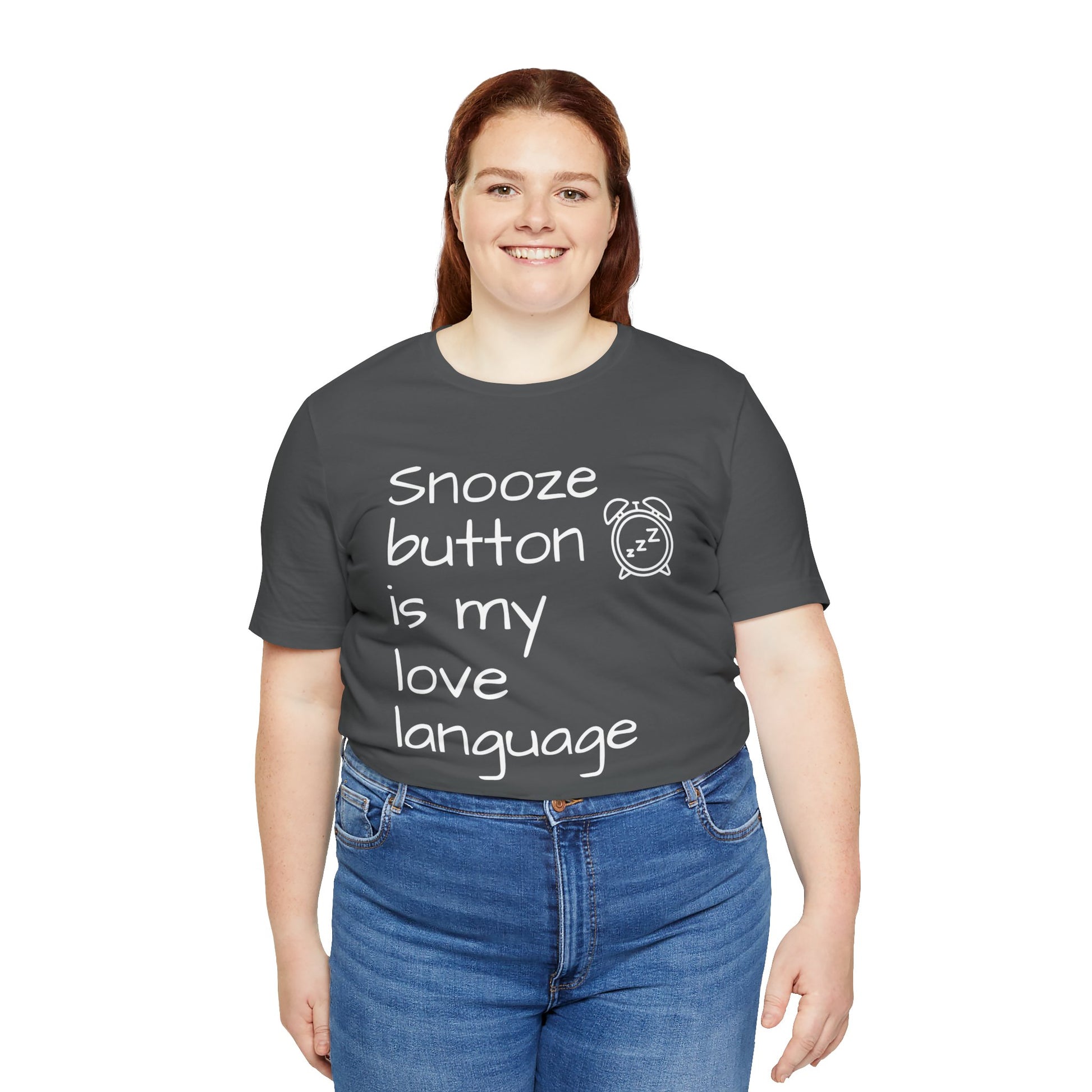 Person wearing a dark gray t-shirt with text 'Snooze button is my love language' and a clock graphic on a white background