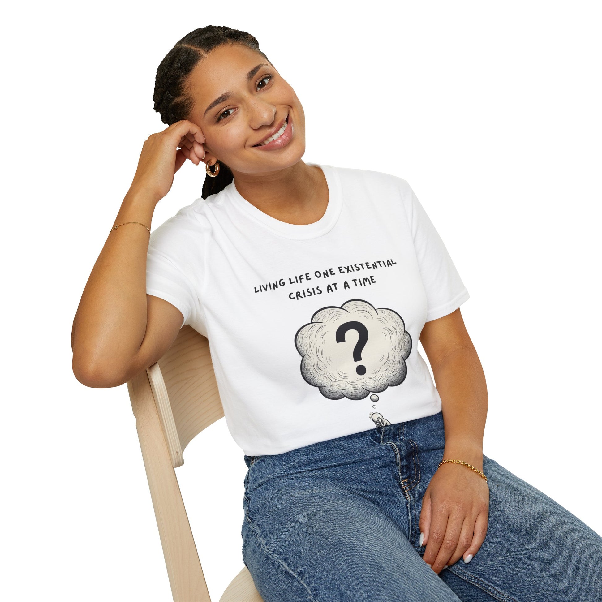 Person wearing a white t-shirt with a graphic and text 'Living Life One Existential Crisis At A Time', sitting on a chair against a white background