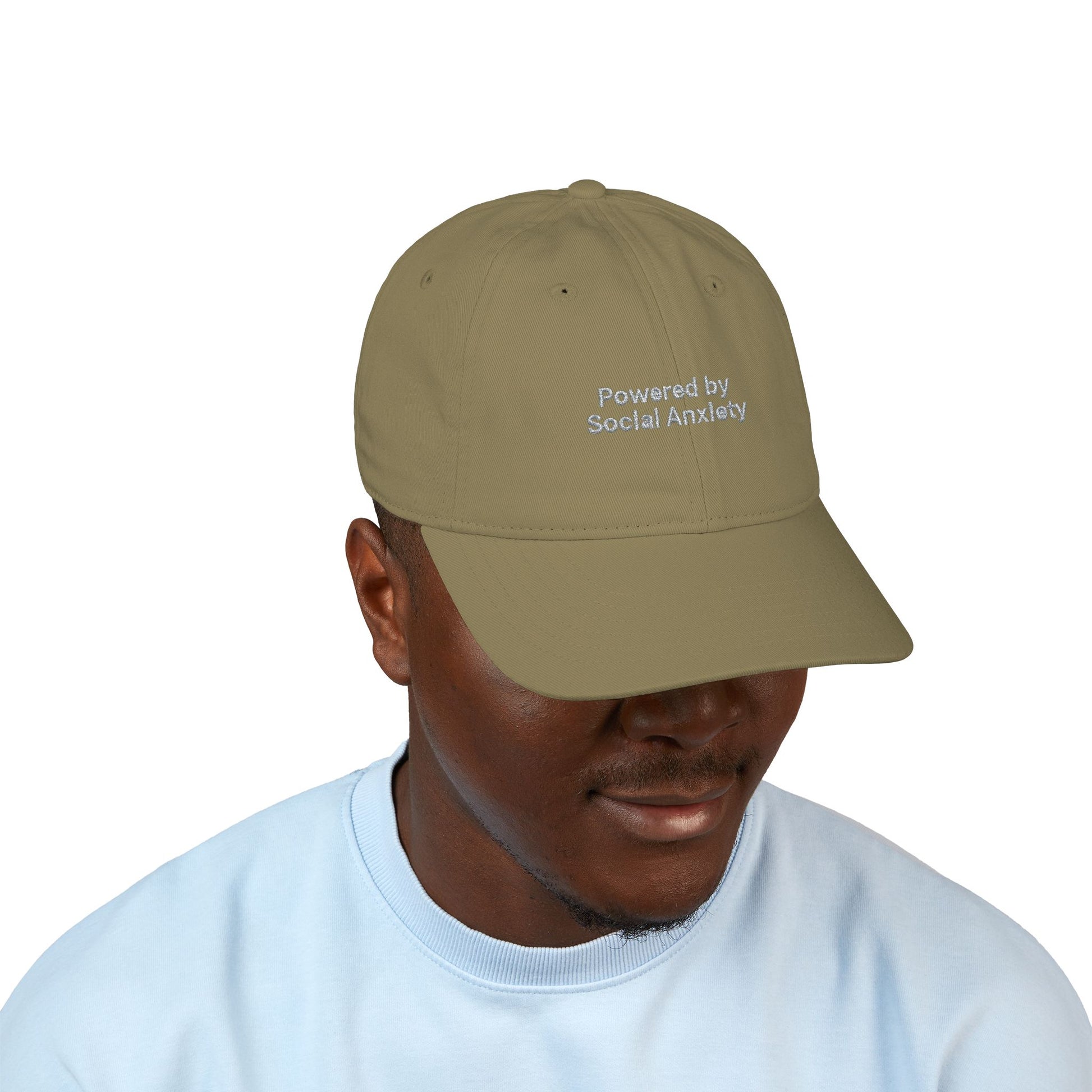 Person wearing a beige cap with 'Powered by Social Anxiety' text on a white background