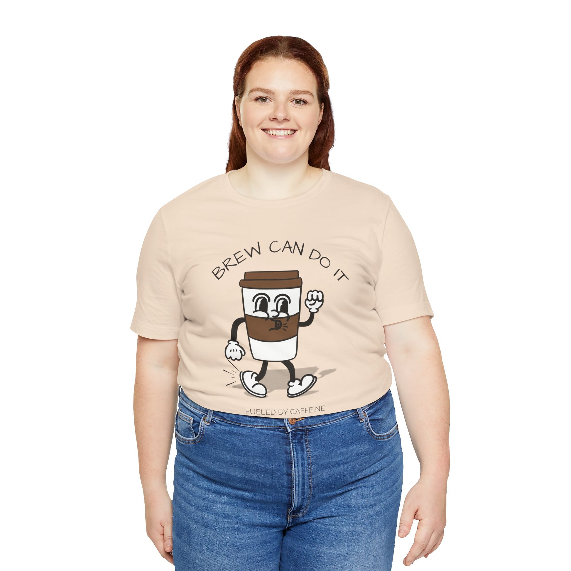Person wearing a beige t-shirt with a coffee-themed graphic and text 'Brew Can Do It Fueled By Caffeine' on a white background