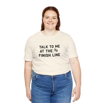 Person wearing a beige t-shirt with 'Talk to me at the finish line' text on a white background