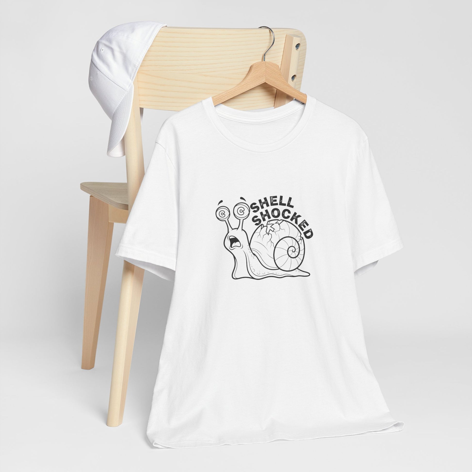 White t-shirt with a snail graphic and 'Shell Shocked' text on a white background