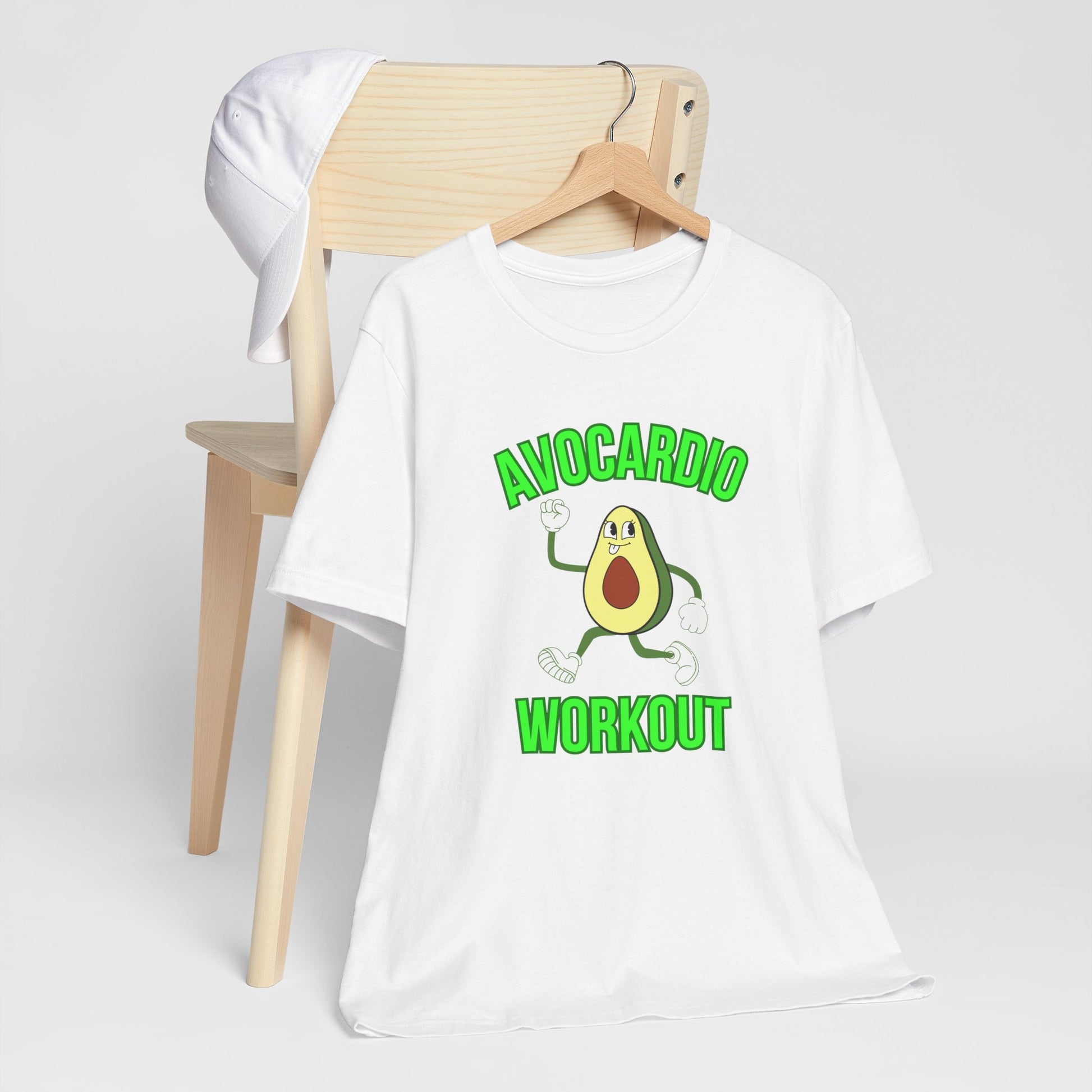 White t-shirt with avocado graphic and text 'Avocardio workout' on a wooden chair against a white background