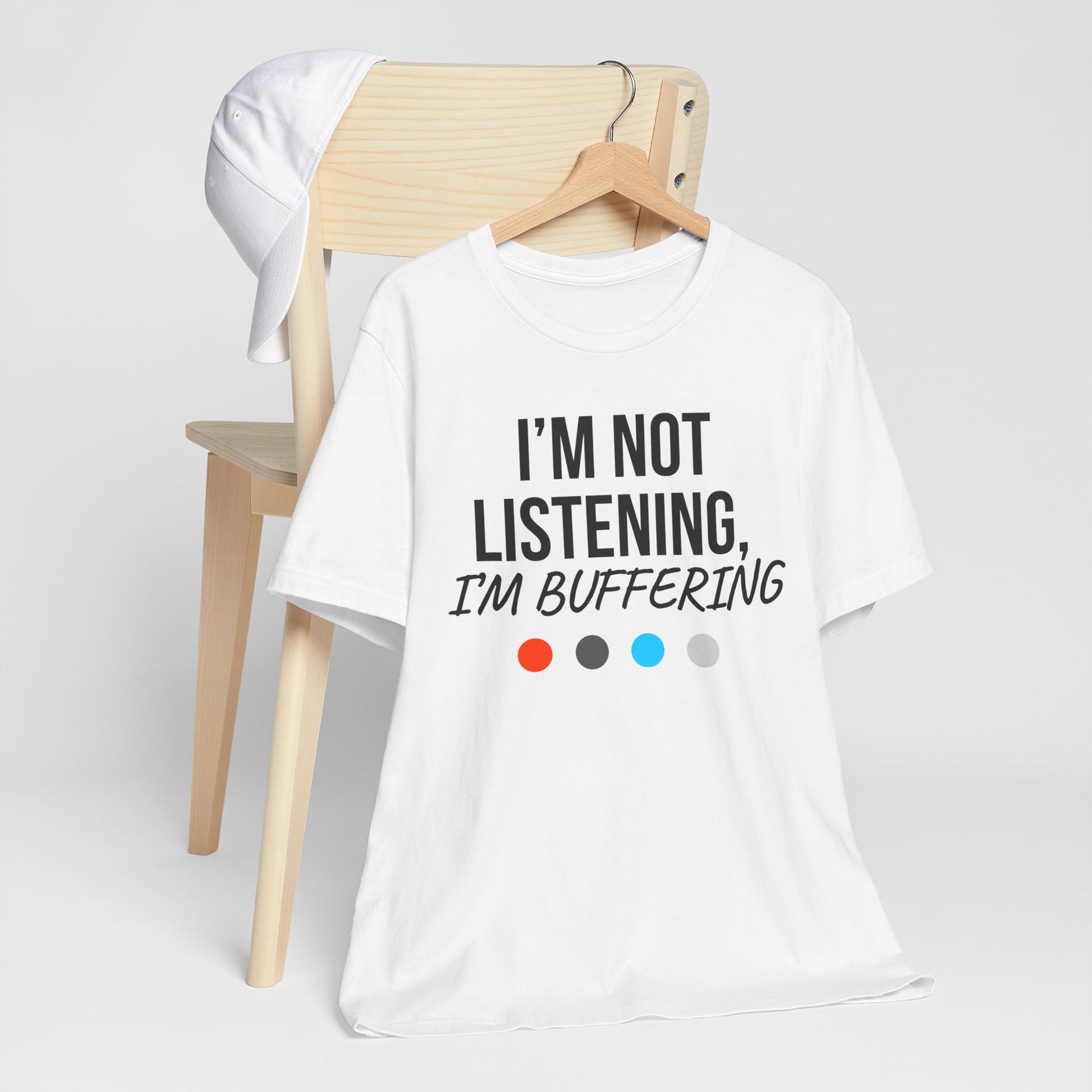White t-shirt with 'I'm not listening, I'm buffering' text on a chair against a white background