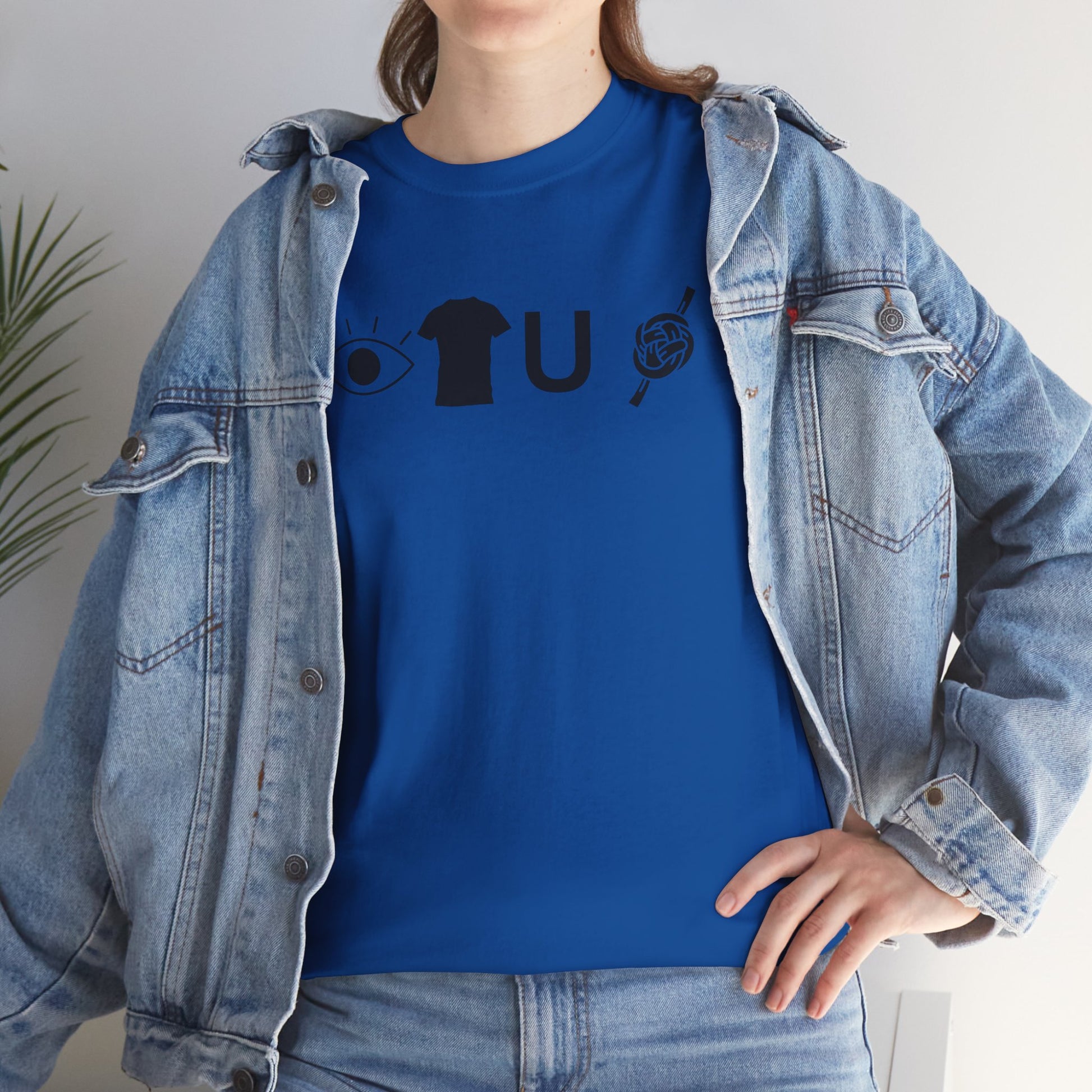 Person wearing a blue shirt with a graphic design and a denim jacket indoors.