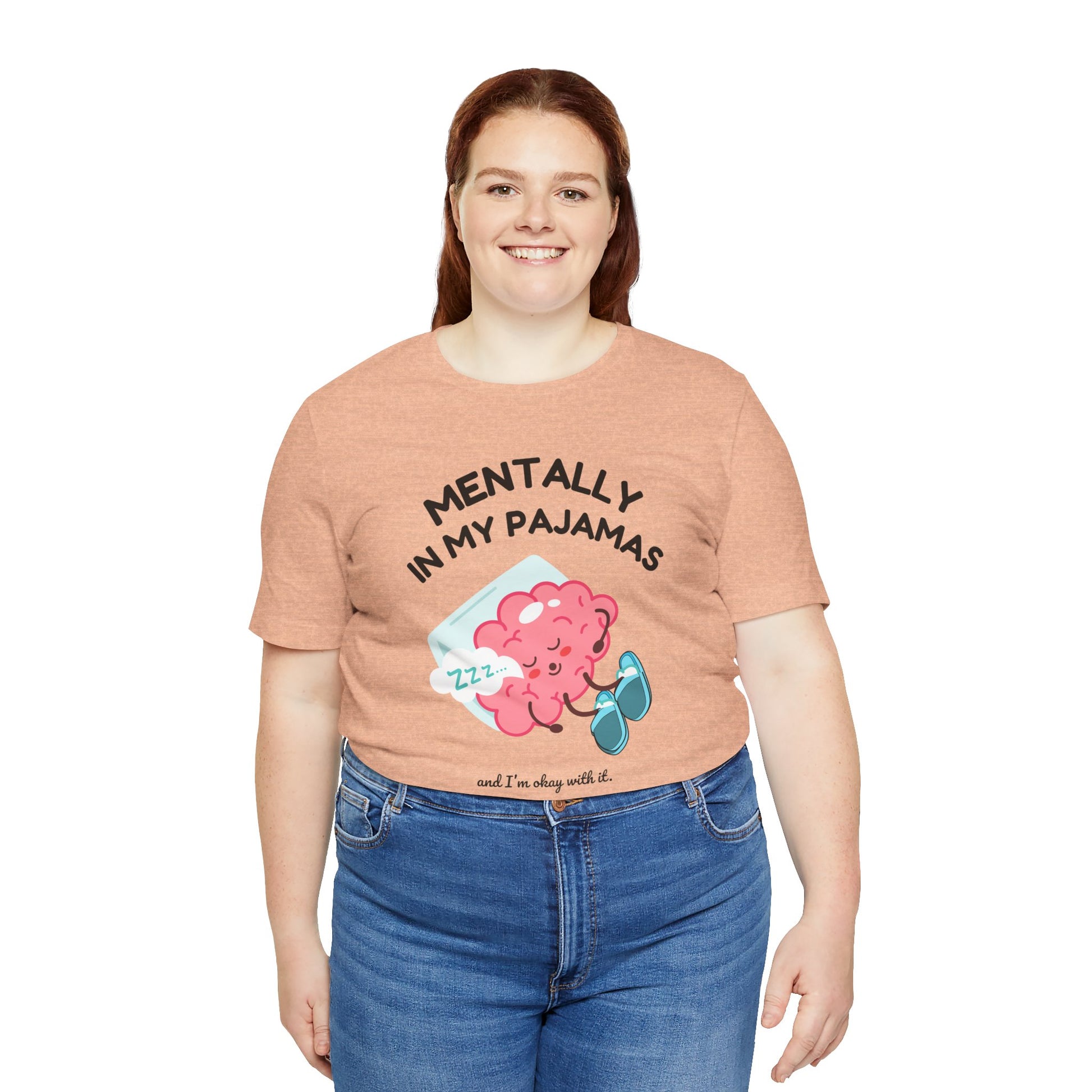 Person wearing a peach t-shirt with a graphic and text 'Mentally in my pajamas and I'm ok with it' on a white background