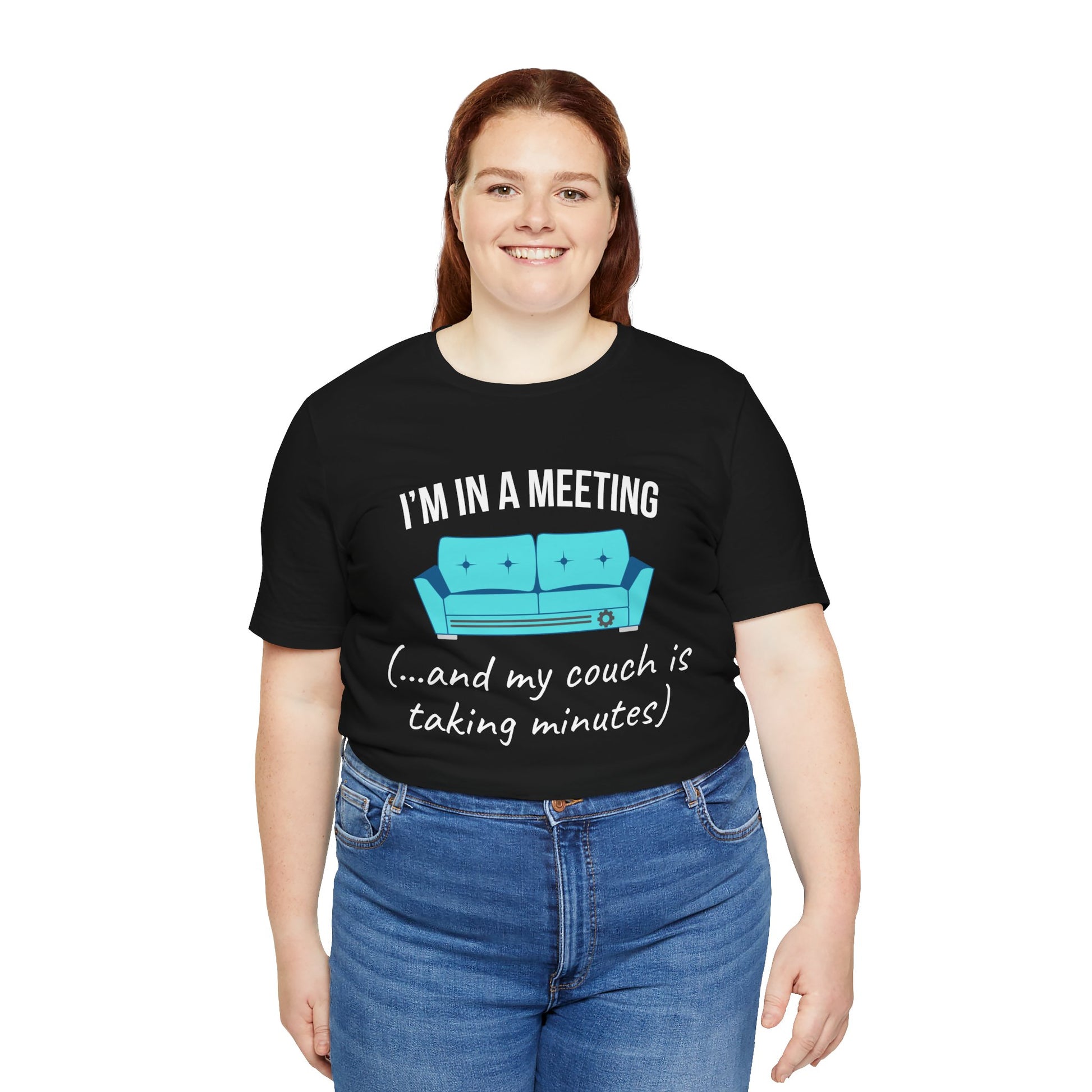 Person wearing a black t-shirt with a humorous graphic and text 'I'm in a meeting (...and my couch is taking minutes)' on a white background