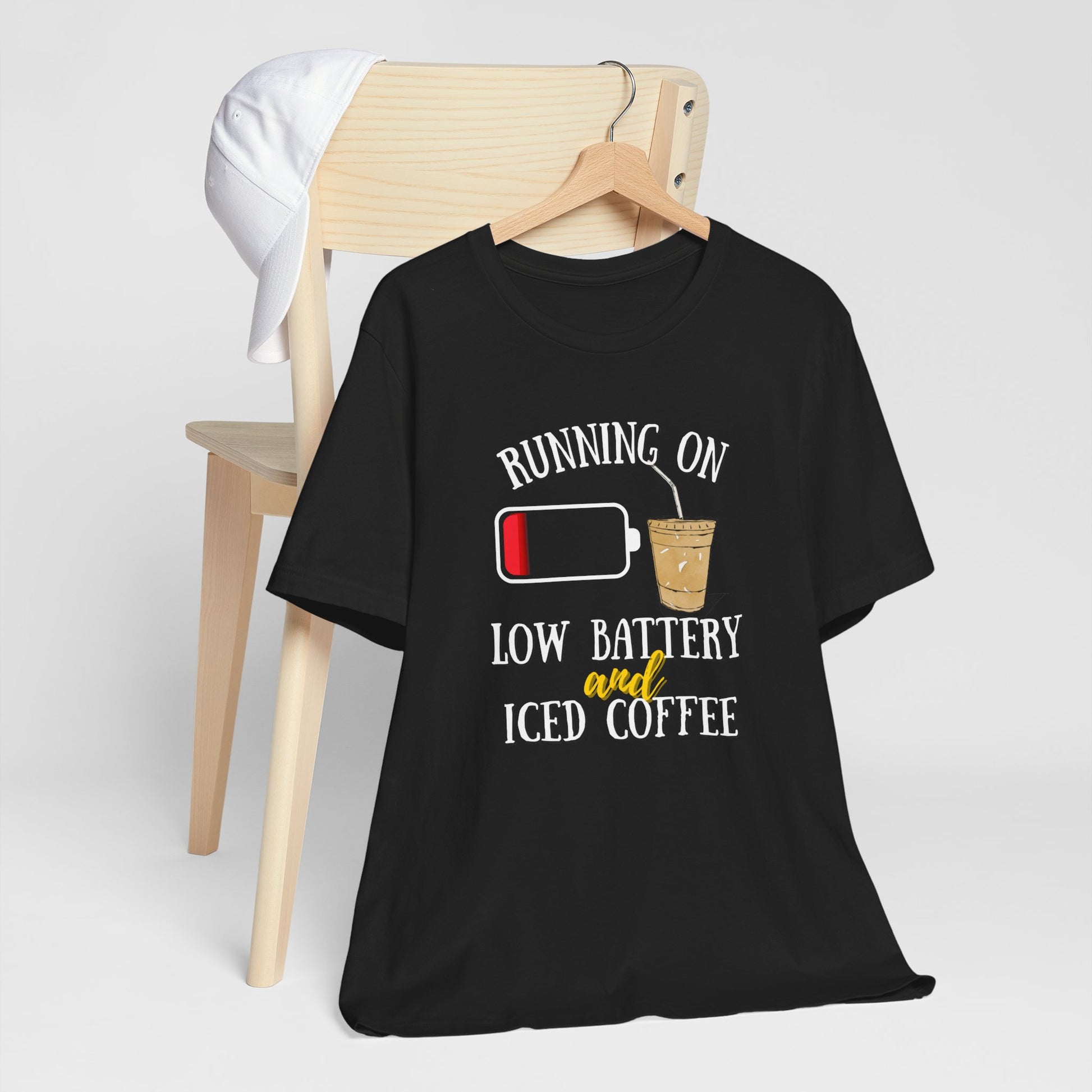 Black t-shirt with 'Running on low battery and iced coffee' text and graphic on a white background