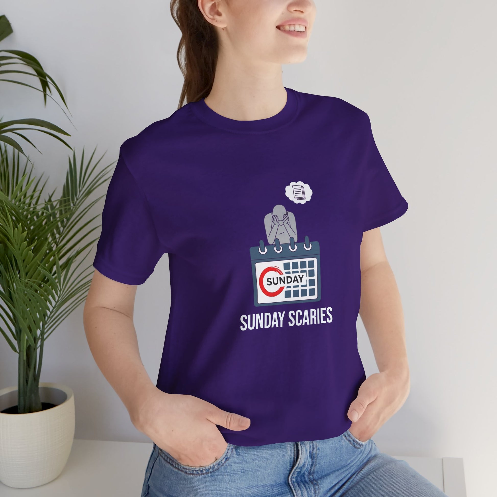Person wearing a purple t-shirt with 'Sunday Scaries' design, standing indoors next to a plant.