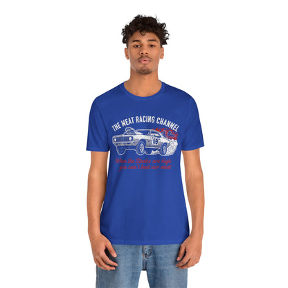 Person wearing a blue Bella+Canvas 3001 T‑shirt featuring a bold drag racing graphic. The design shows a vintage muscle car with the number 69, white smoke and red flames, the distressed white title “The Meat Racing Channel” above, and the red script tagline “When the Steaks are high you can’t beat our meat” below. Funny drag racing parody shirt with retro hot rod style, perfect for car enthusiasts, gearheads, and humor‑driven racing apparel fans.