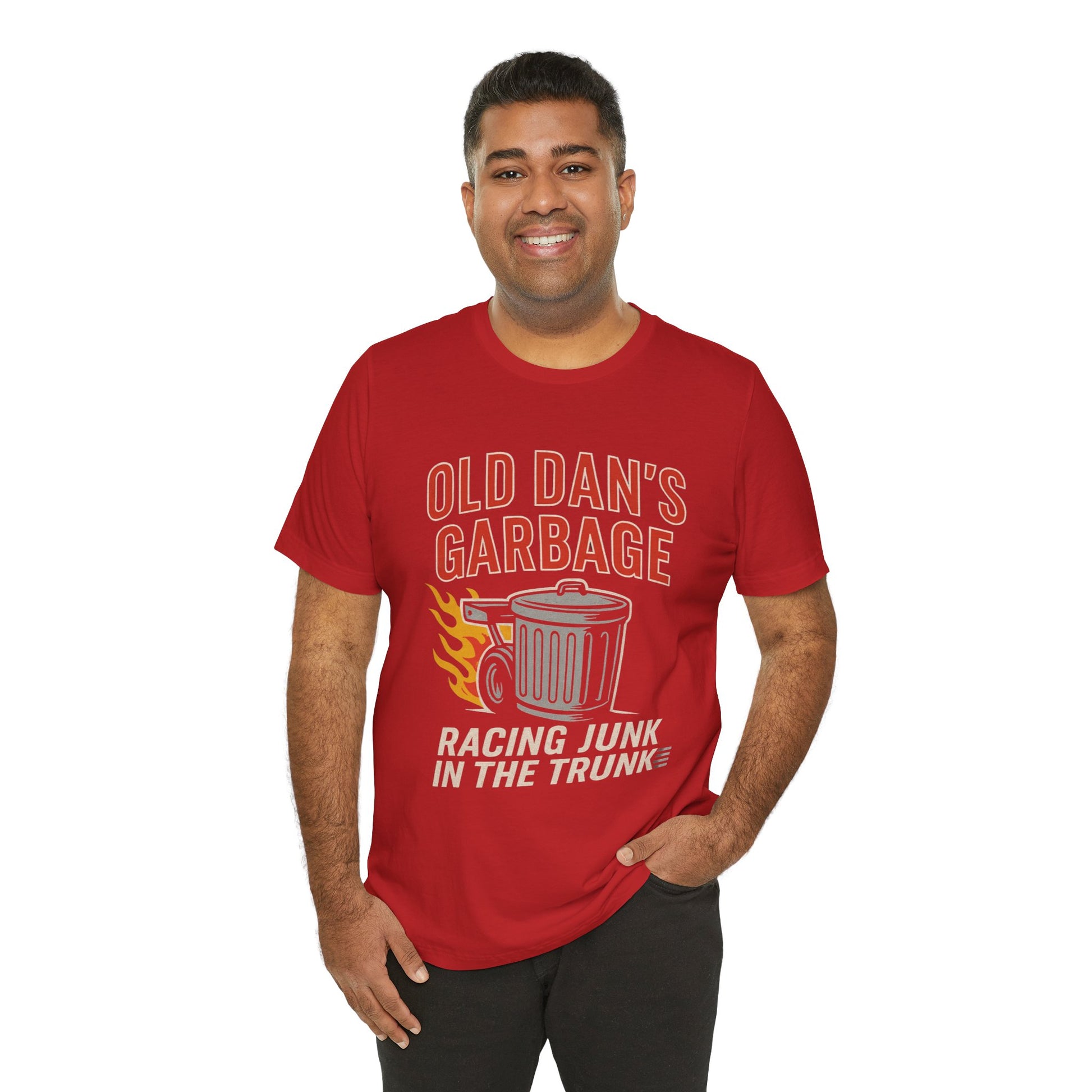 Person wearing a red graphic T‑shirt featuring the bold red and white text “Old Dan’s Garbage” above a flaming garbage can illustration, with the tagline “Racing Junk in the Trunk” below. Funny drag racing parody shirt with retro racing flames, checkered flag background, and humor‑driven hot rod style, perfect for car enthusiasts and gearhead apparel fans.