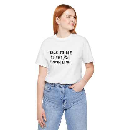 Person wearing a white t-shirt with text 'Talk to me at the finish line' on a white background
