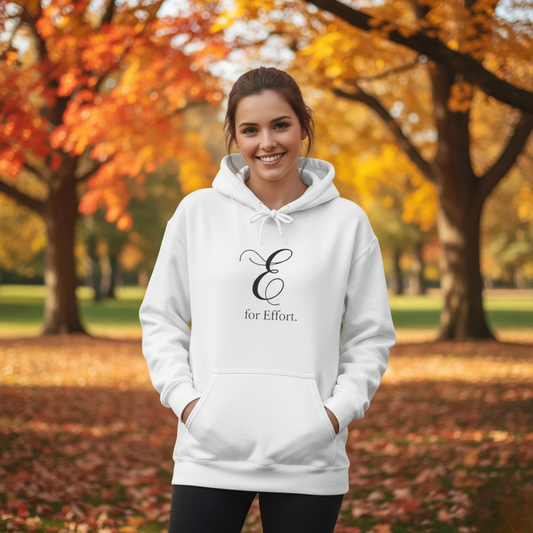 Woman wearing a white hoodie with a logo and text 'E for Effort' in an autumn park