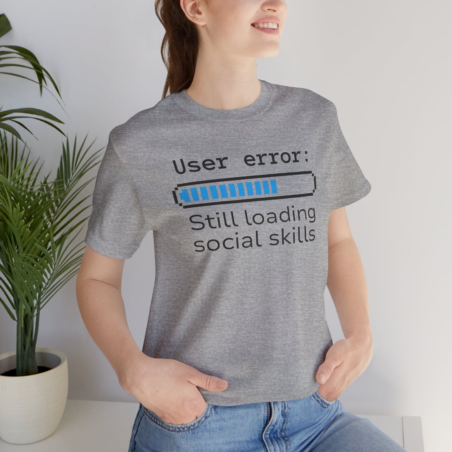 Person wearing a Bella+Canvas 3001 t-shirt in athletic heather with text that says User error: Still loading social skills. 