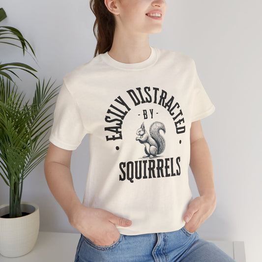Person wearing a white t-shirt with a squirrel graphic and text 'EASILY DISTRACTED BY SQUIRRELS', standing against a plain background.