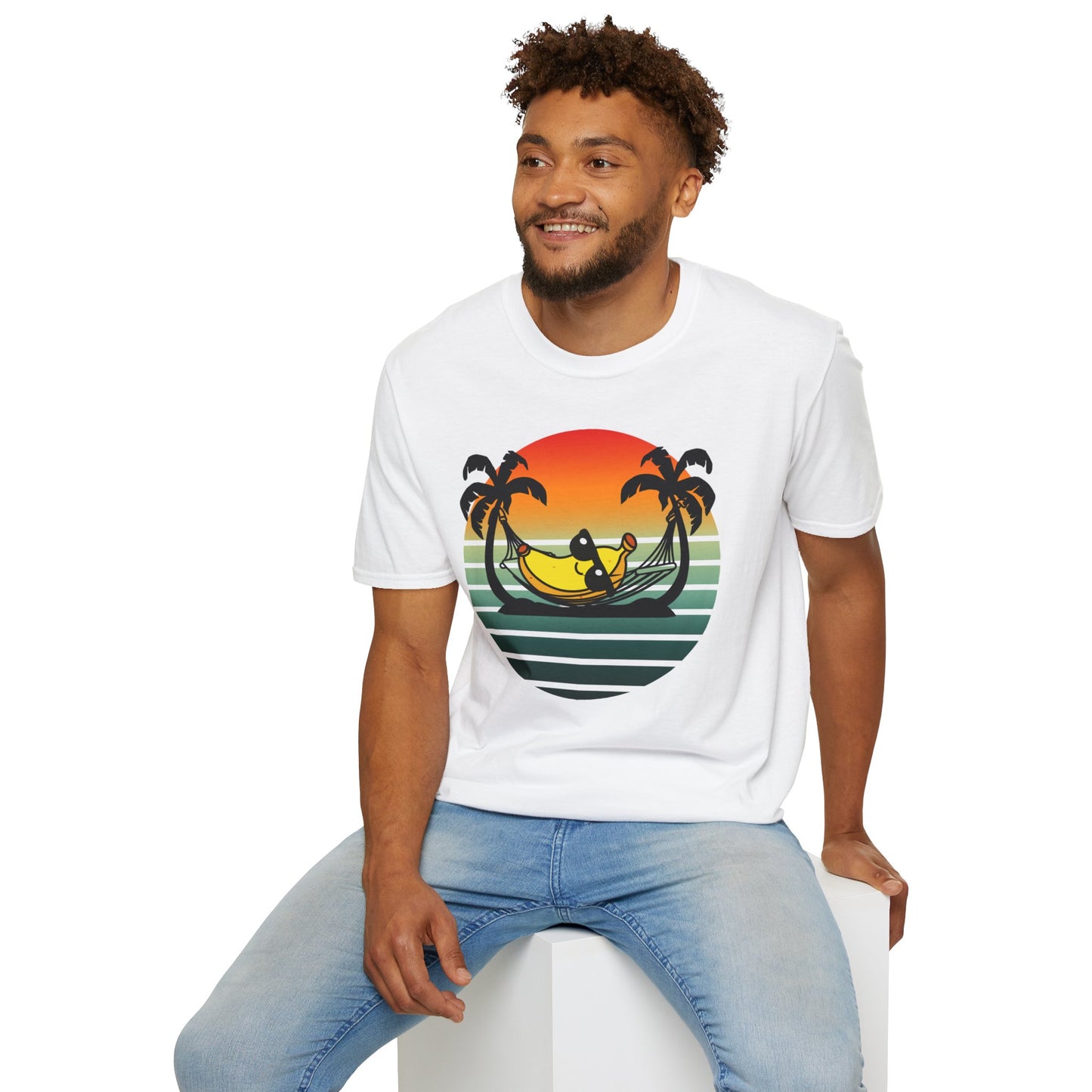Man wearing a white t-shirt with a tropical 'banana hammock' design sitting on a white stool against a white background