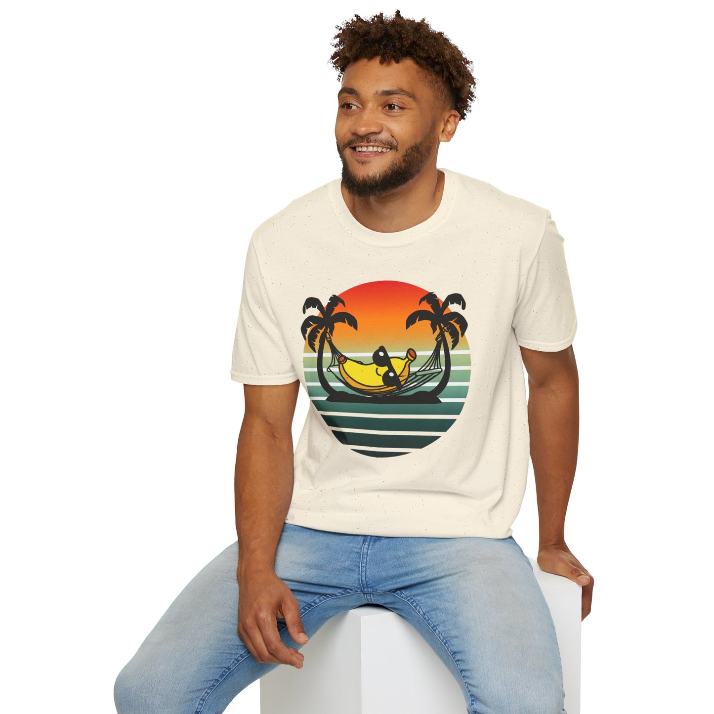 Man wearing a t-shirt with a tropical 'banana hammock' design sitting on a white stool against a white background