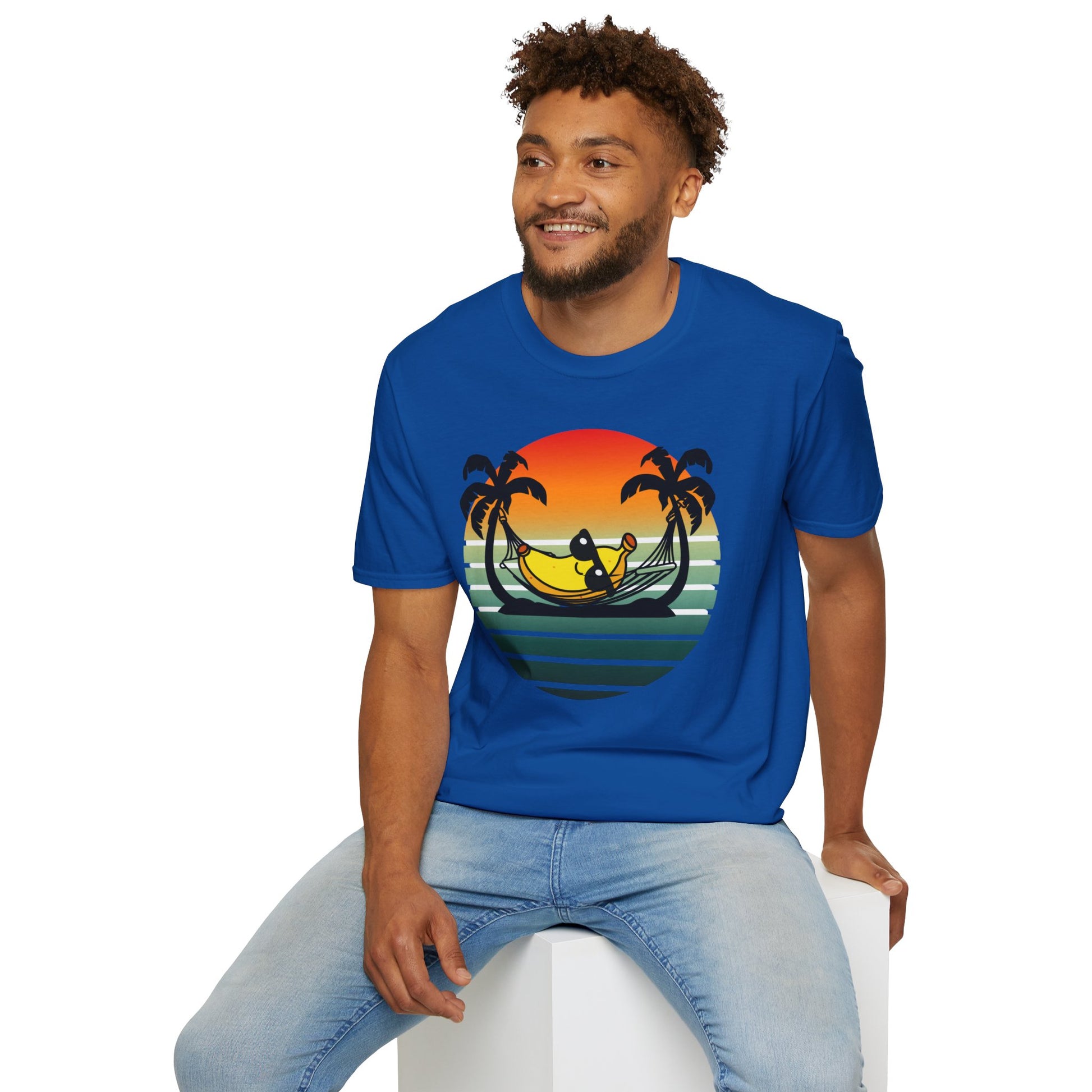 Man wearing a blue t-shirt with a tropical 'banana hammock' design sitting on a white stool.